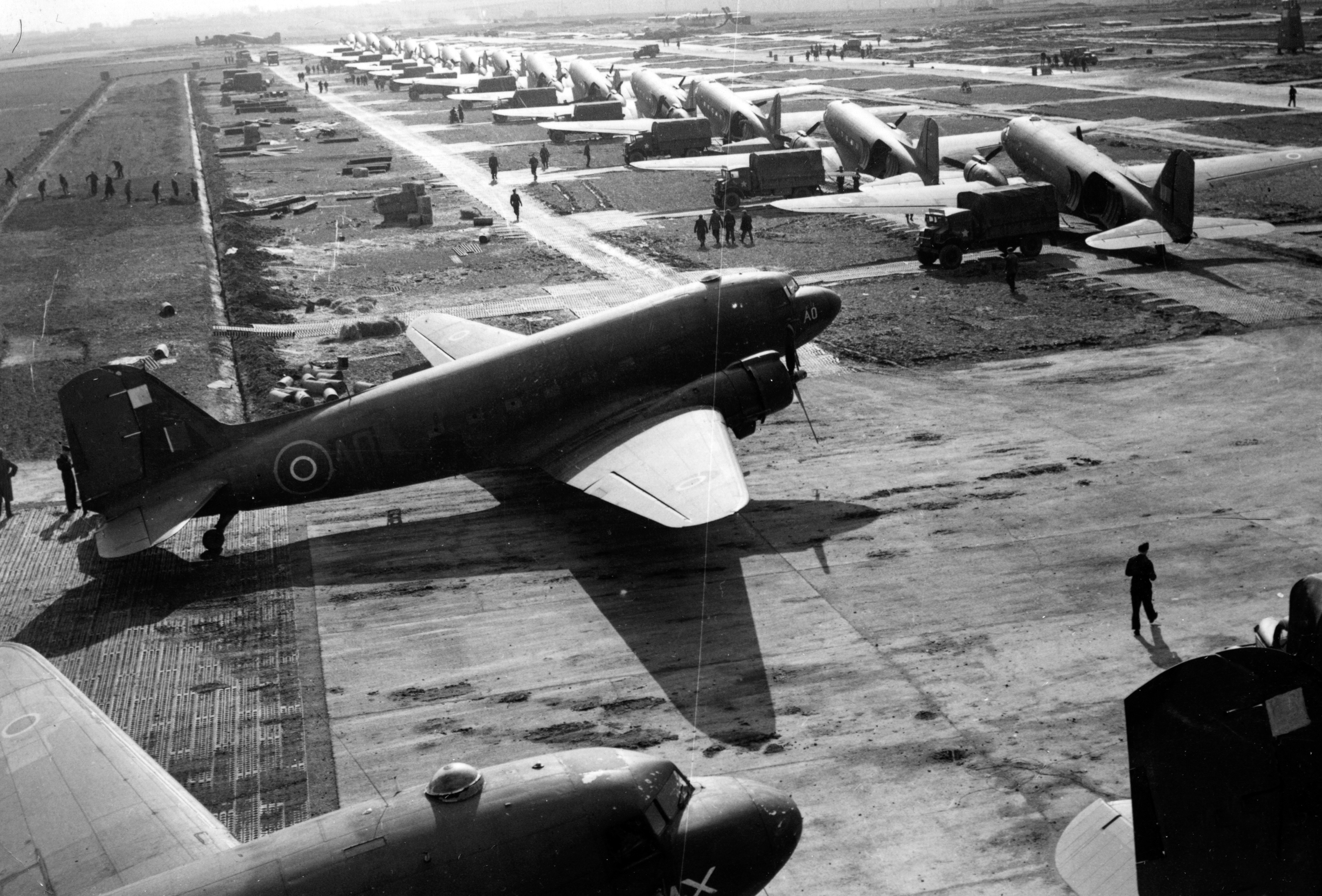 Douglas Dakotas on the airfield being unloaded by Army lorries.
