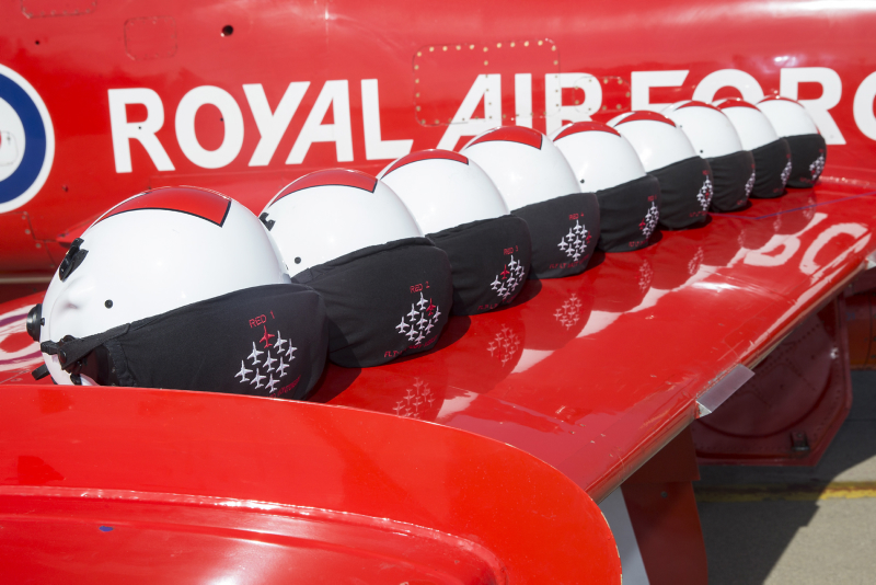 Image shows white pilot helmets resting on the wing of a Red Arrow aircraft.