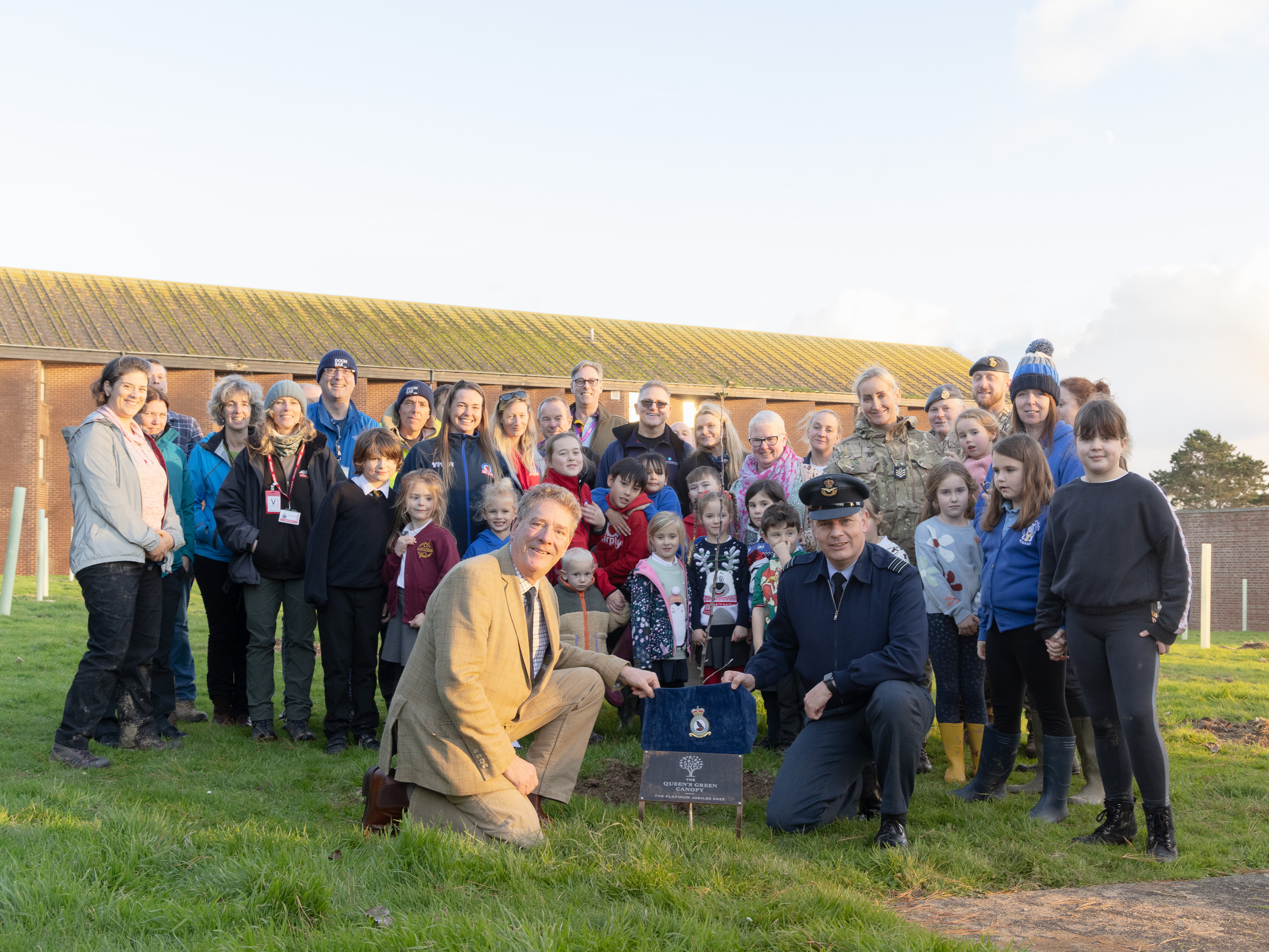 Image shows community and RAF aviators gathered for photo with the plaque.