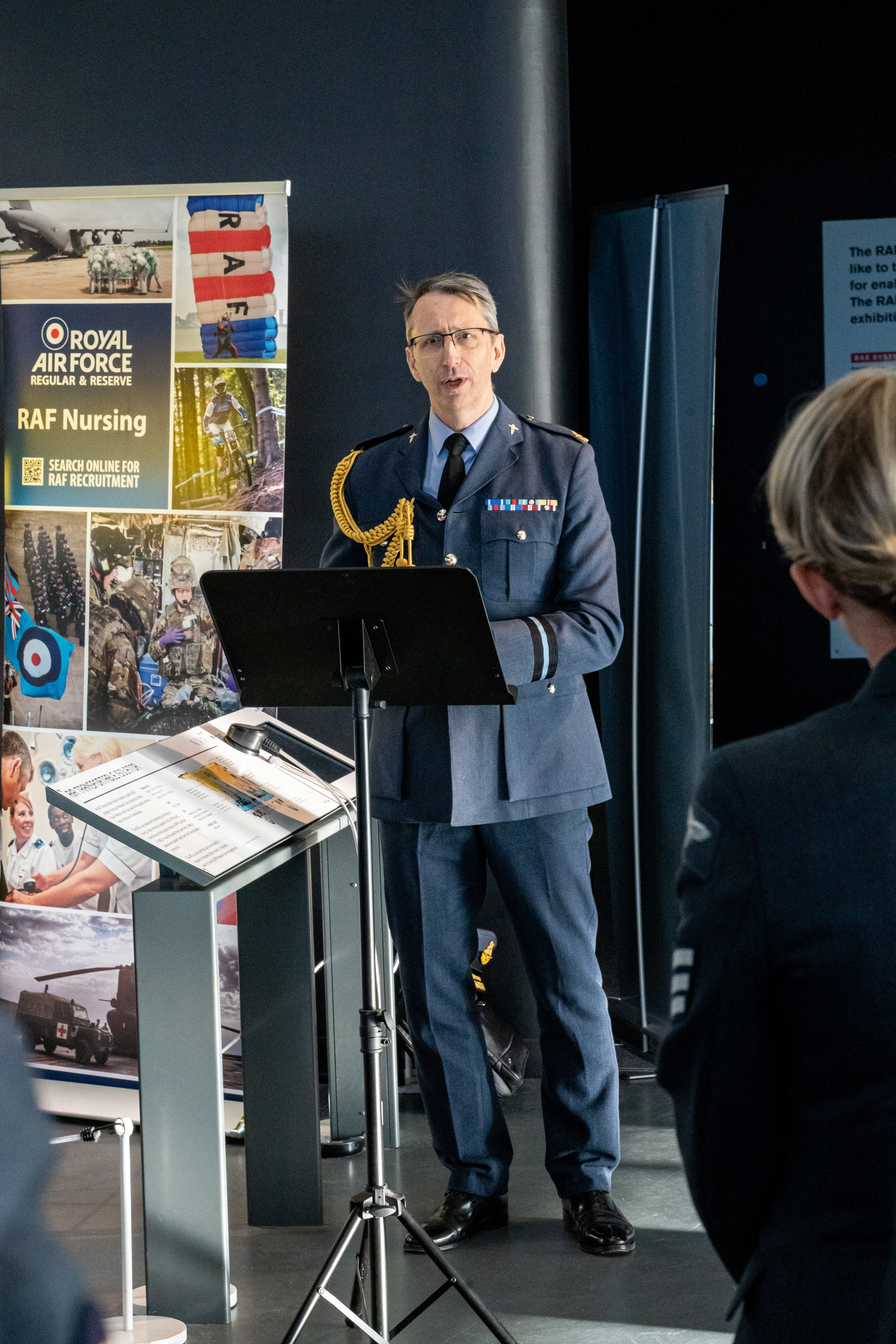 Personnel stands at oration stand in museum.