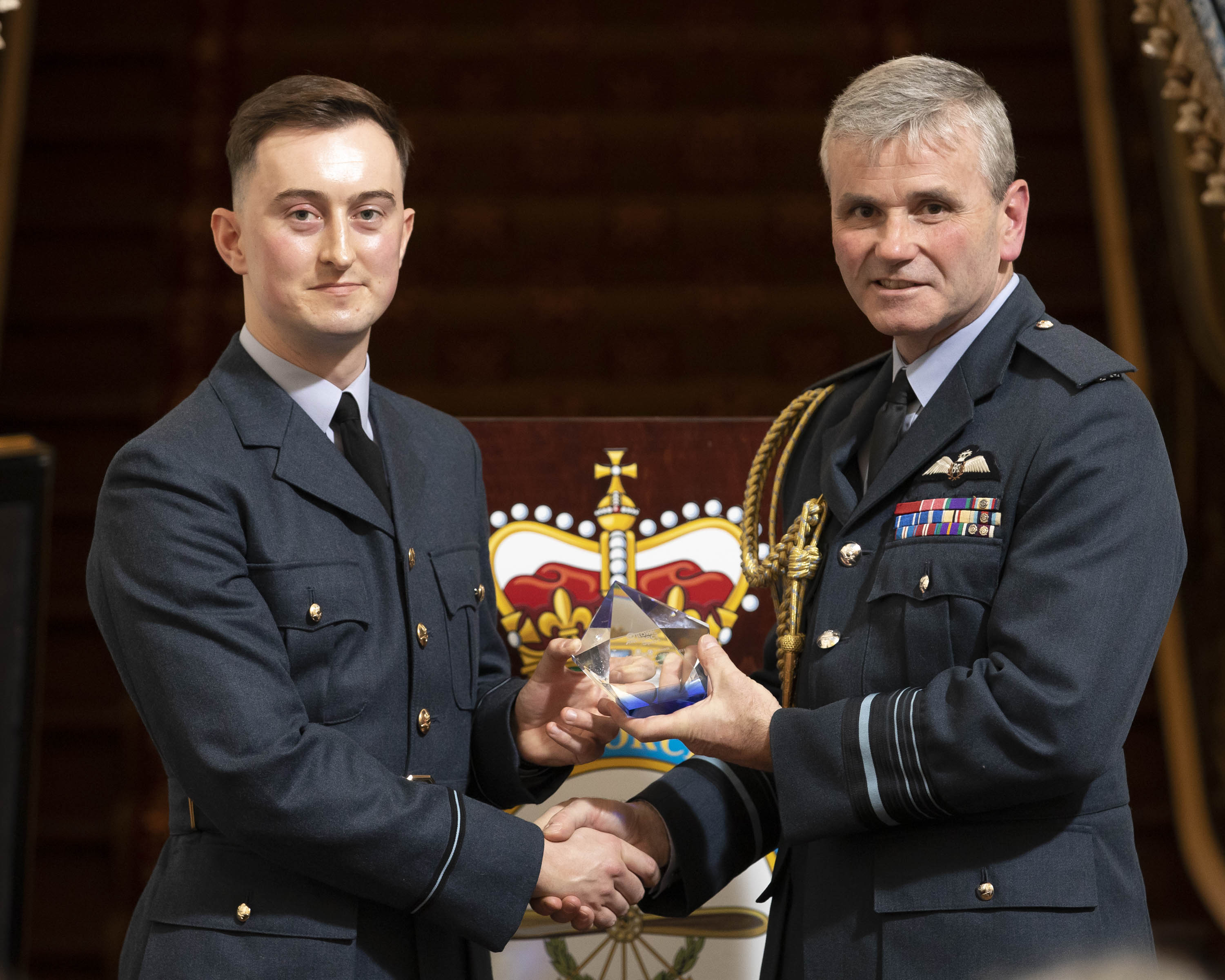 Flying Officer Hilton shakes hands with Air Marshall Andrew Turner while accepting his award.
