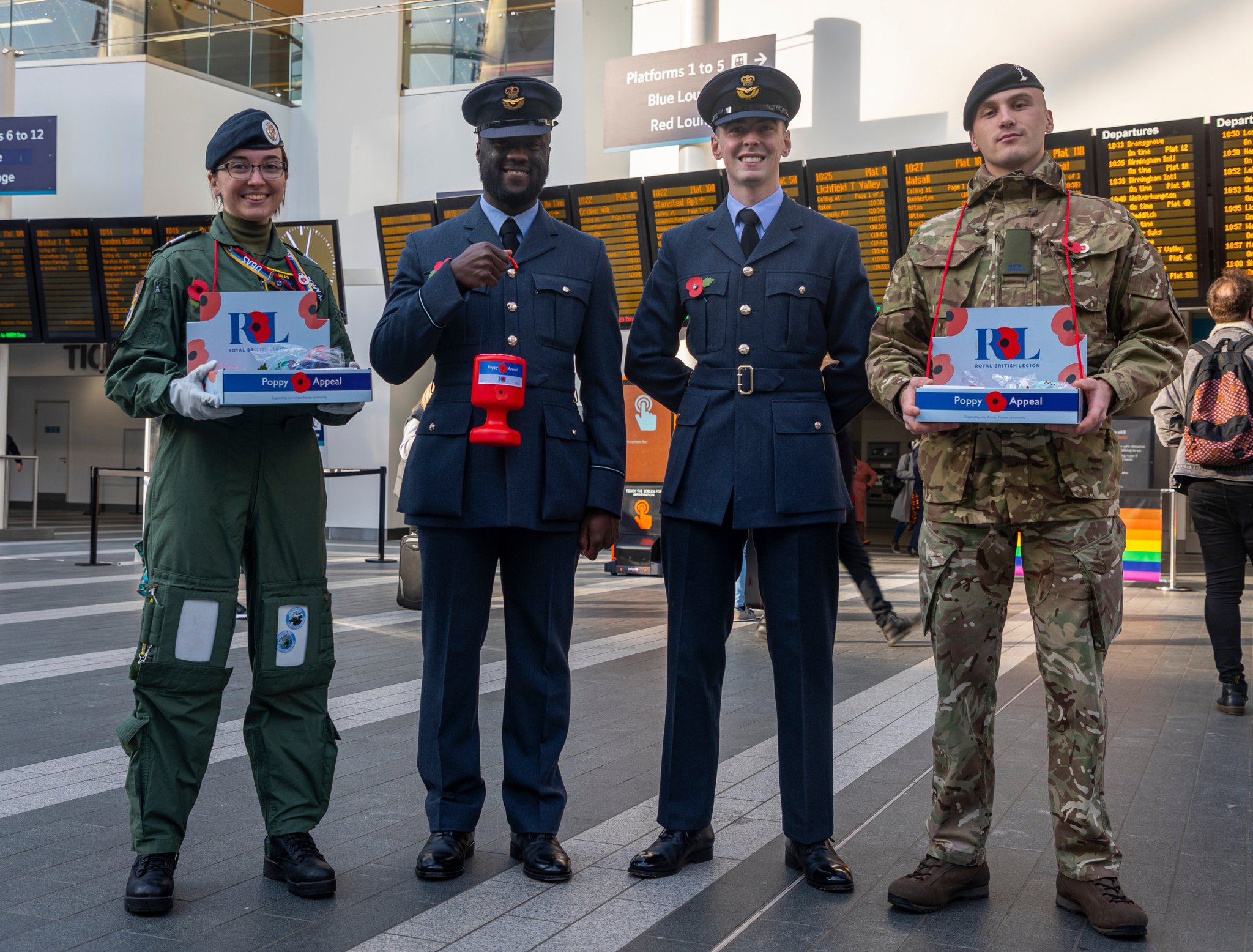 Personnel stand in a train station with Poppy bucket collections. 
