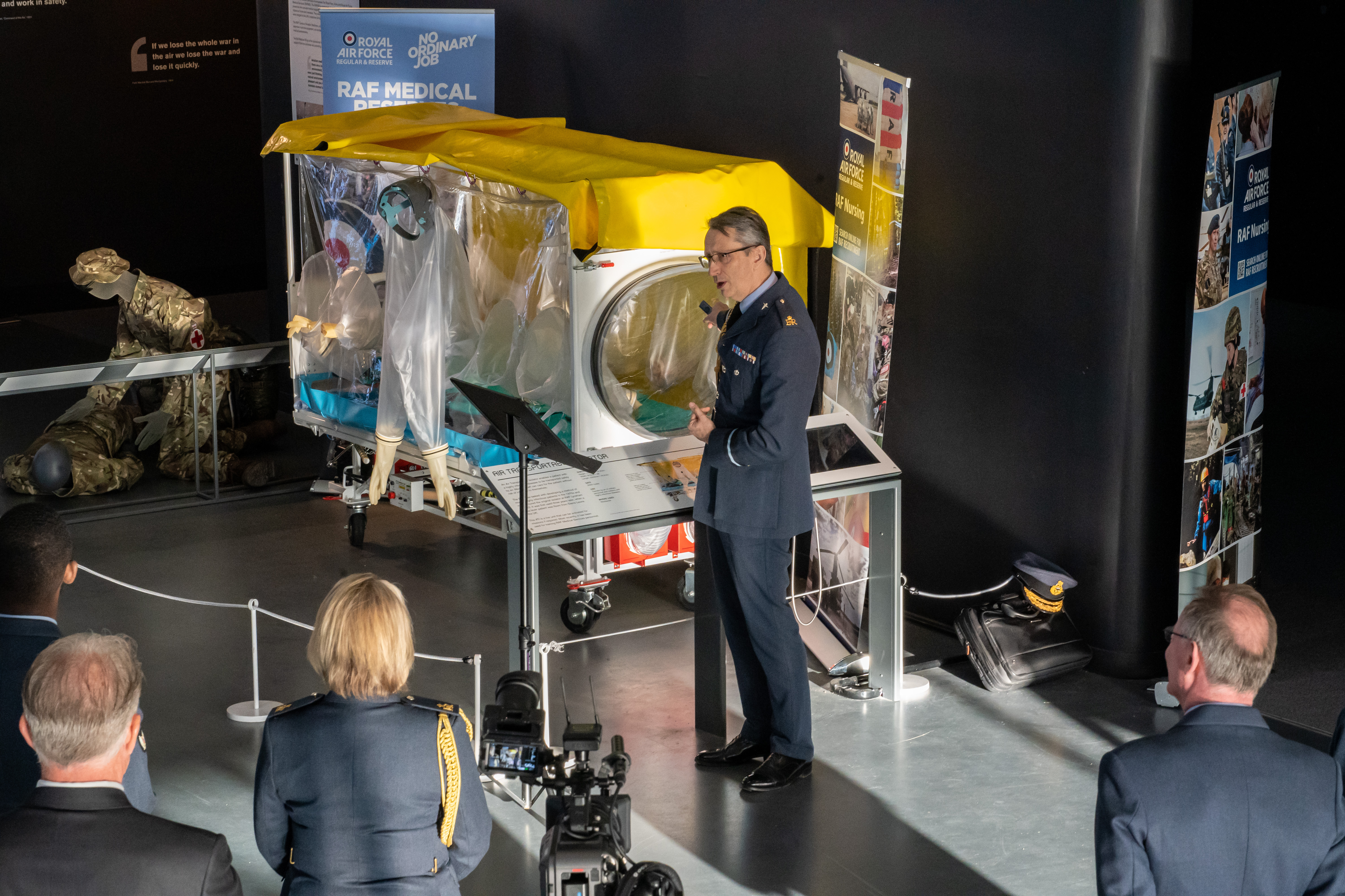 Personnel stands by exhibition quarantine bed, talking to crowd.