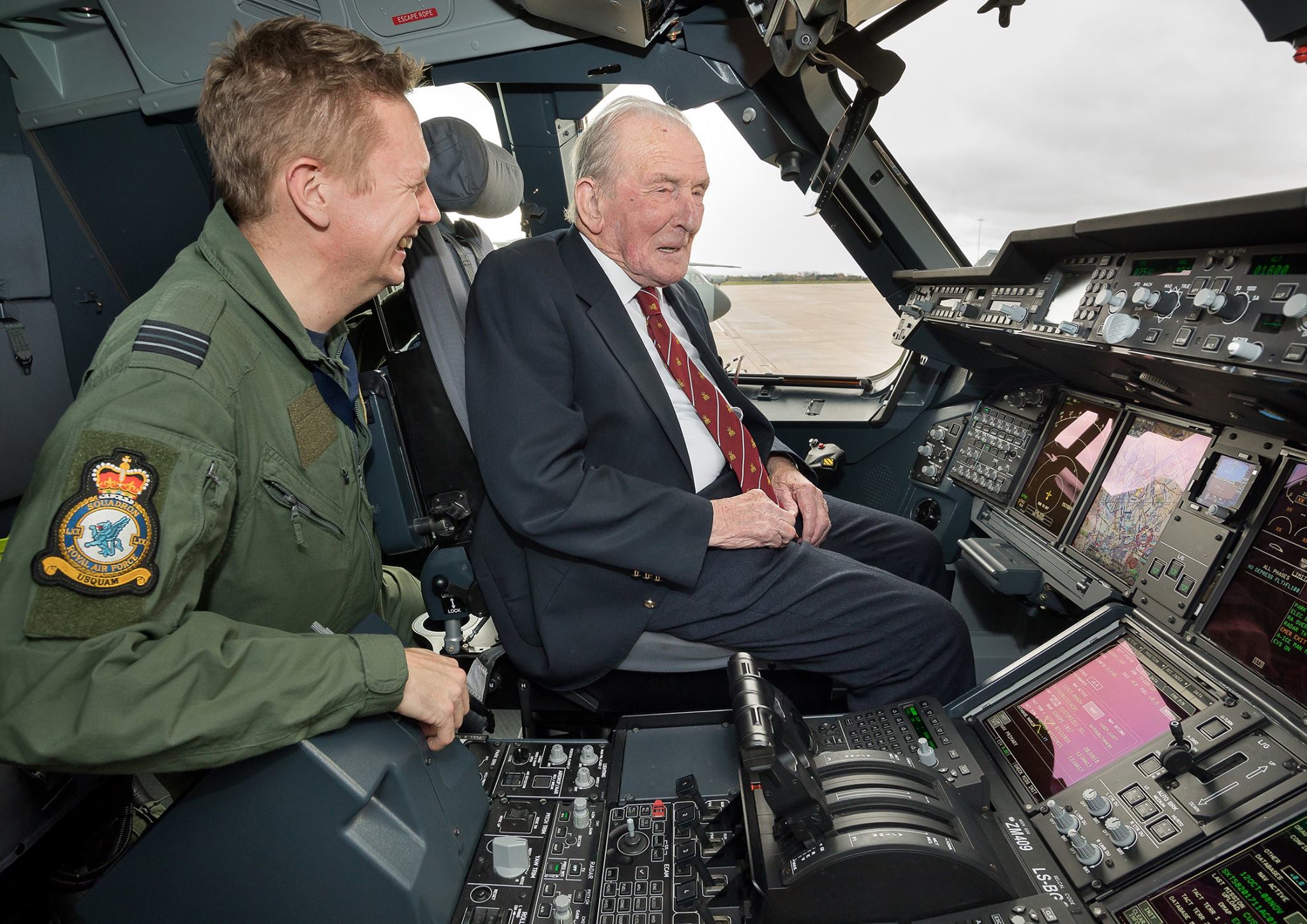 Johnny with a pilot in the cockpit of an aircraft.
