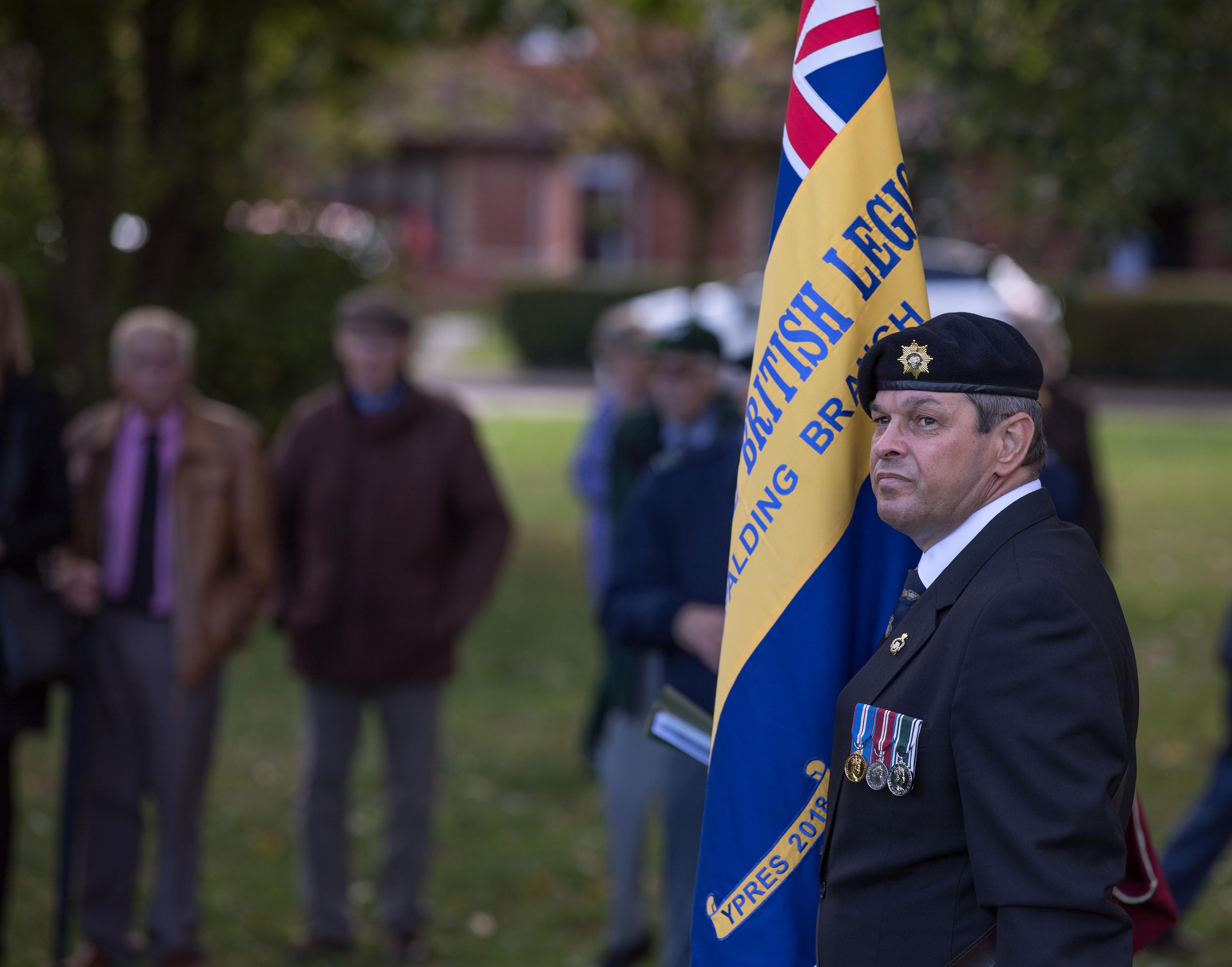 Personnel stands with British Legion flag.