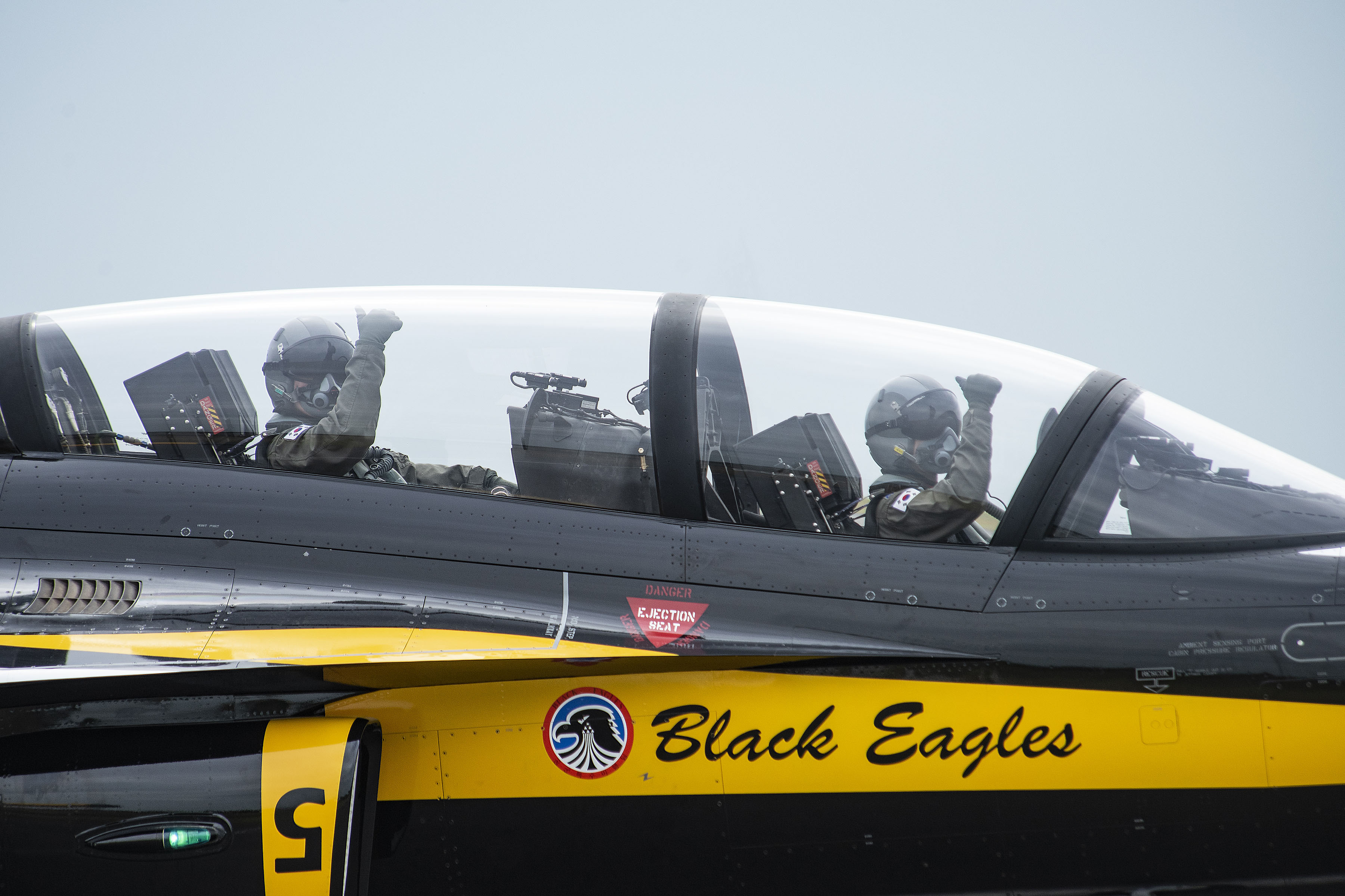 Image shows two Korean Air Force Pilots giving the thumbs up from the cockpit of a Black Eagle.