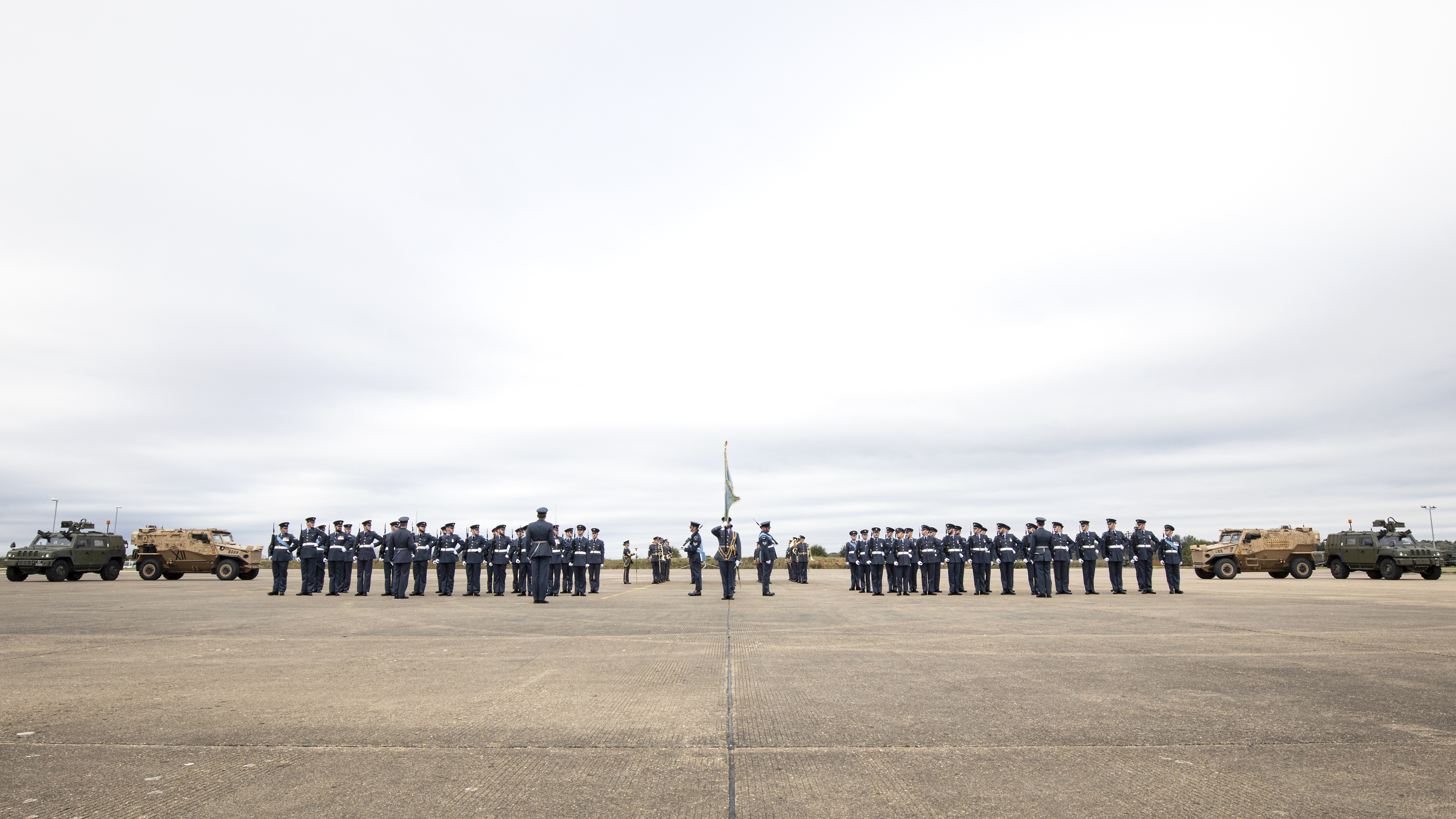 Personnel on parade with vehicles.