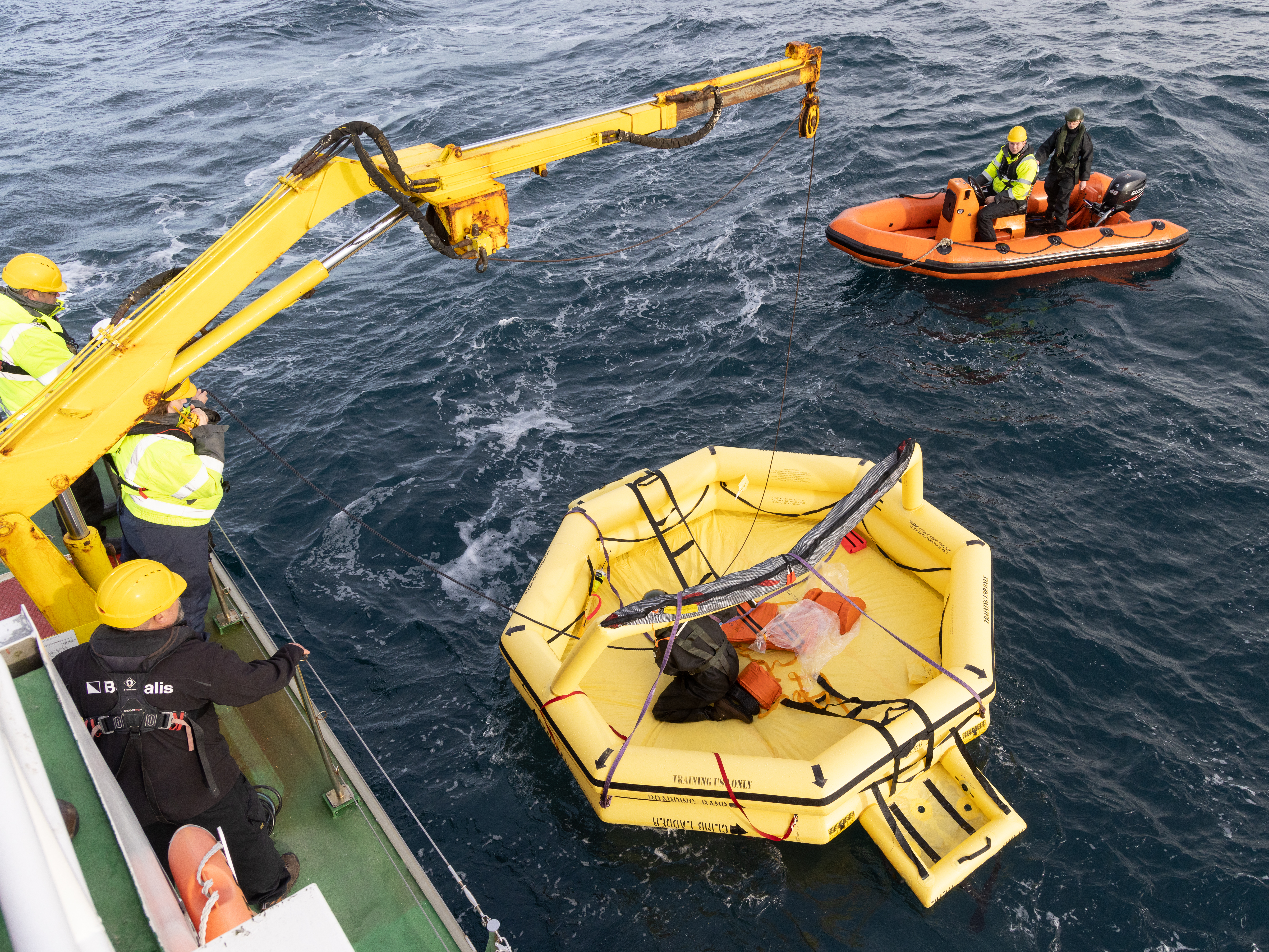 Image shows RAF Search and Rescue team as a lifeboat is lifted out of the sea.