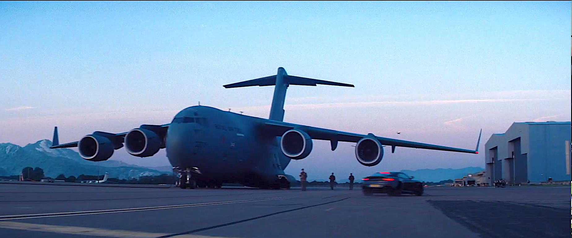 The C-17 Globemaster on the runway with sports car driving past.