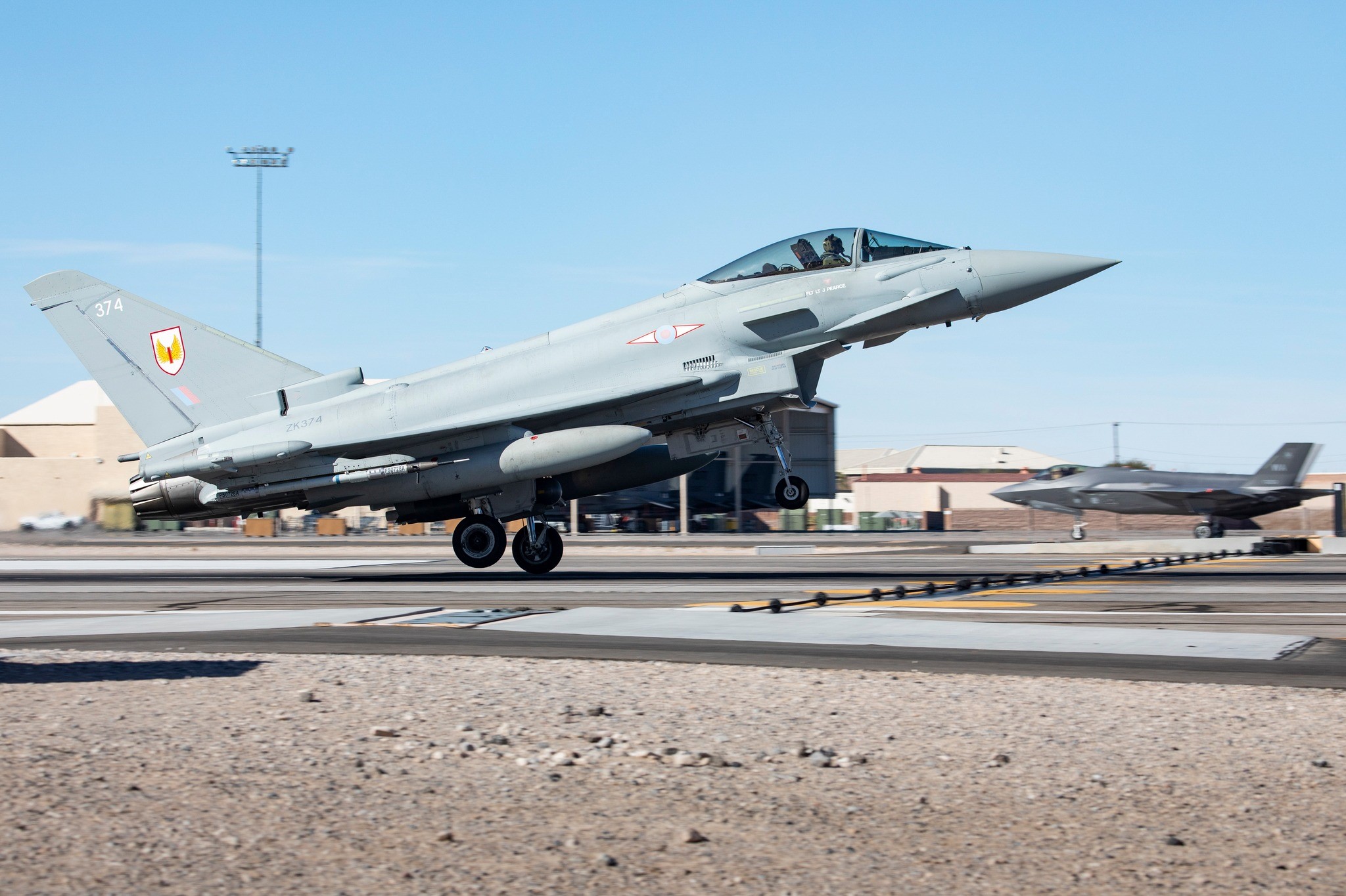 Fighter jet about to take off, with grounded Typhoon in the background.
