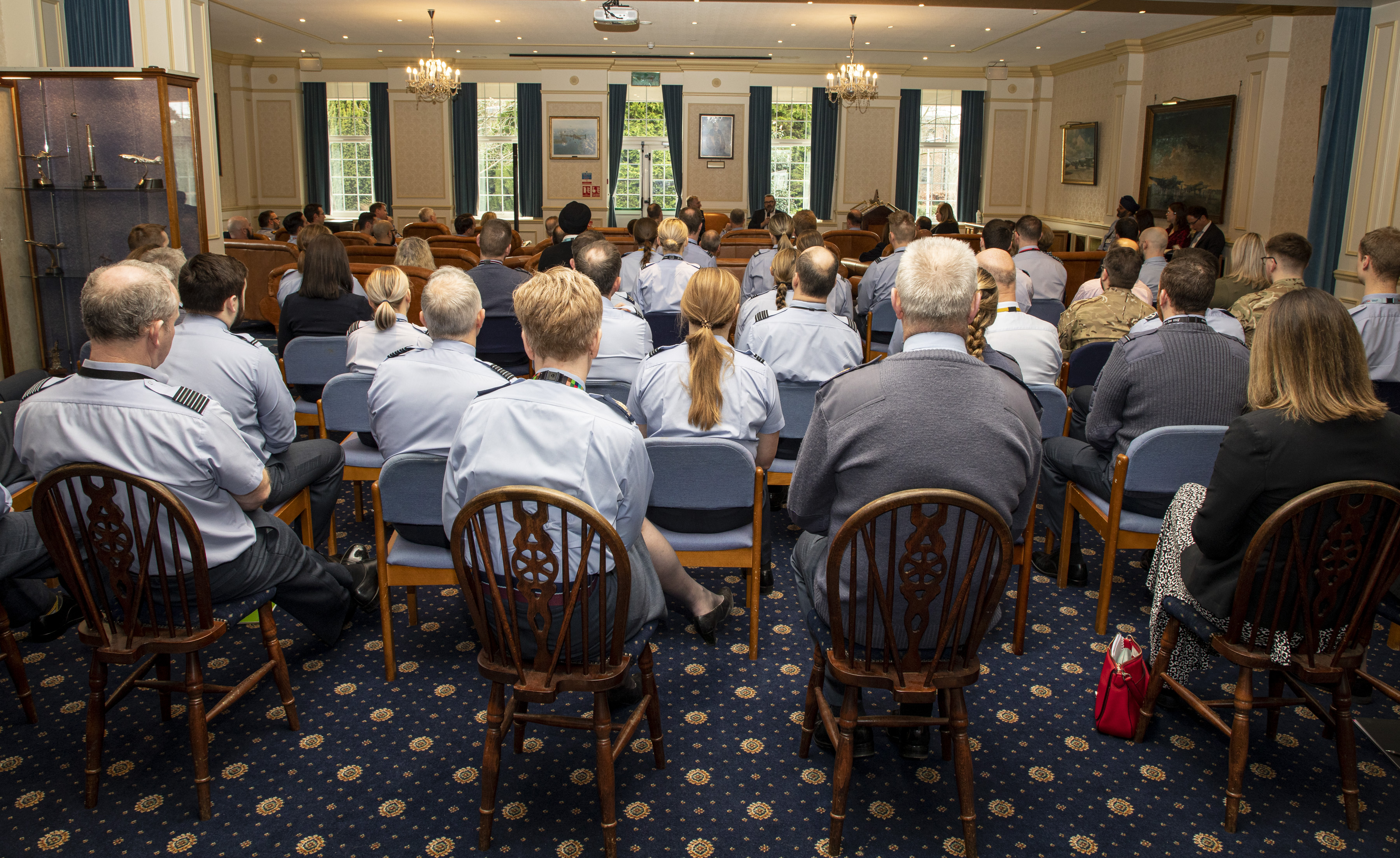 Personnel sit on chair in room.