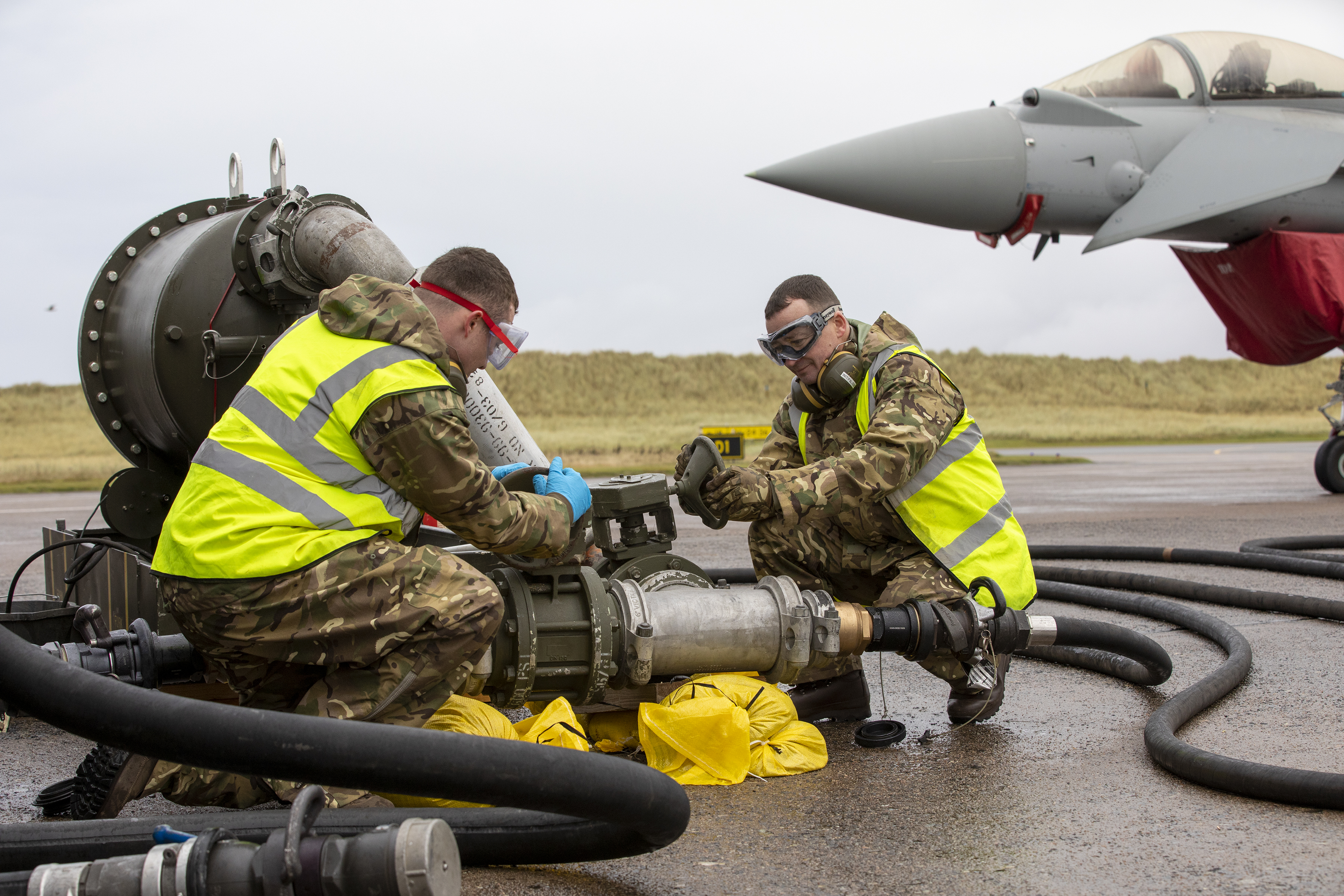 Personnel work on aircraft parts, with Typhoon in the background.