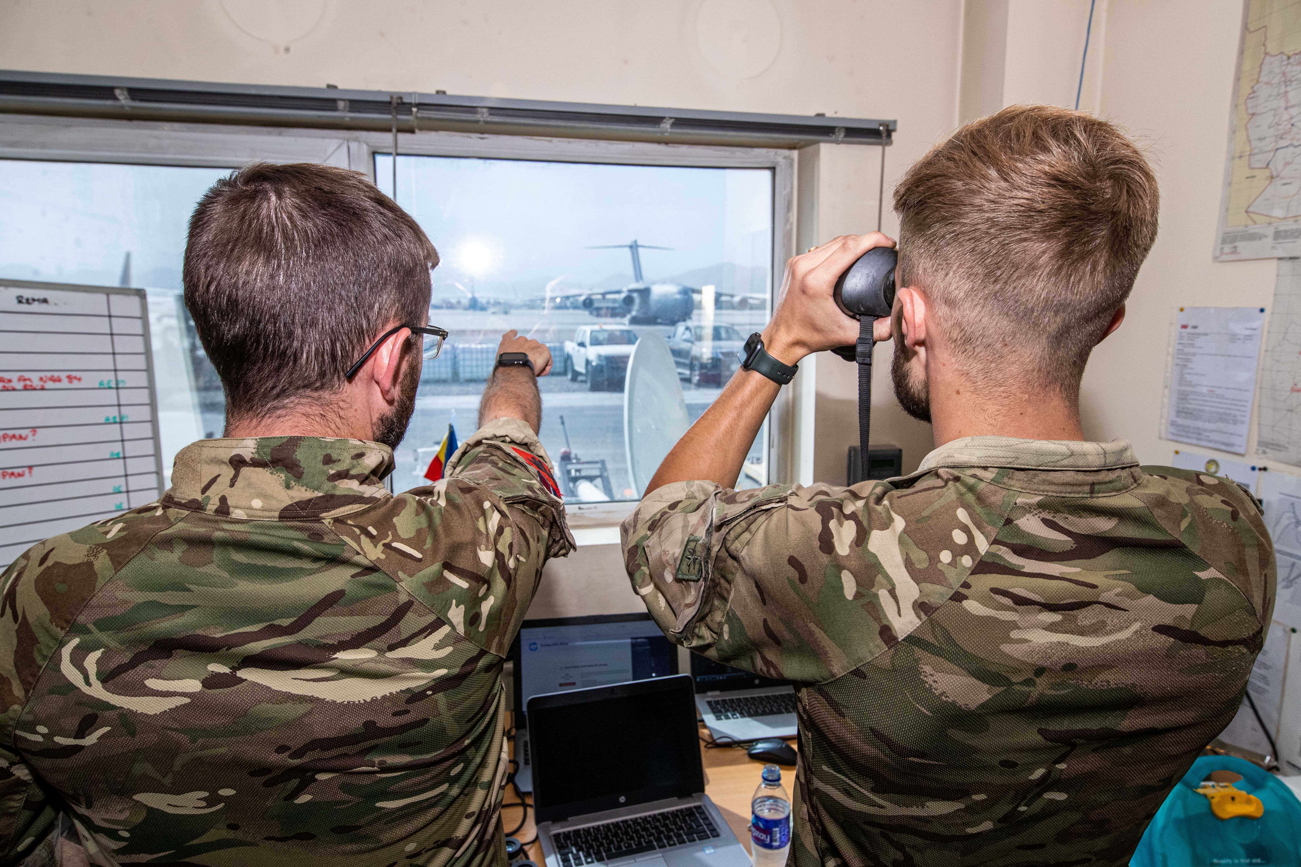 One personnel uses binoculars while another points towards the Voyager on the runaway.