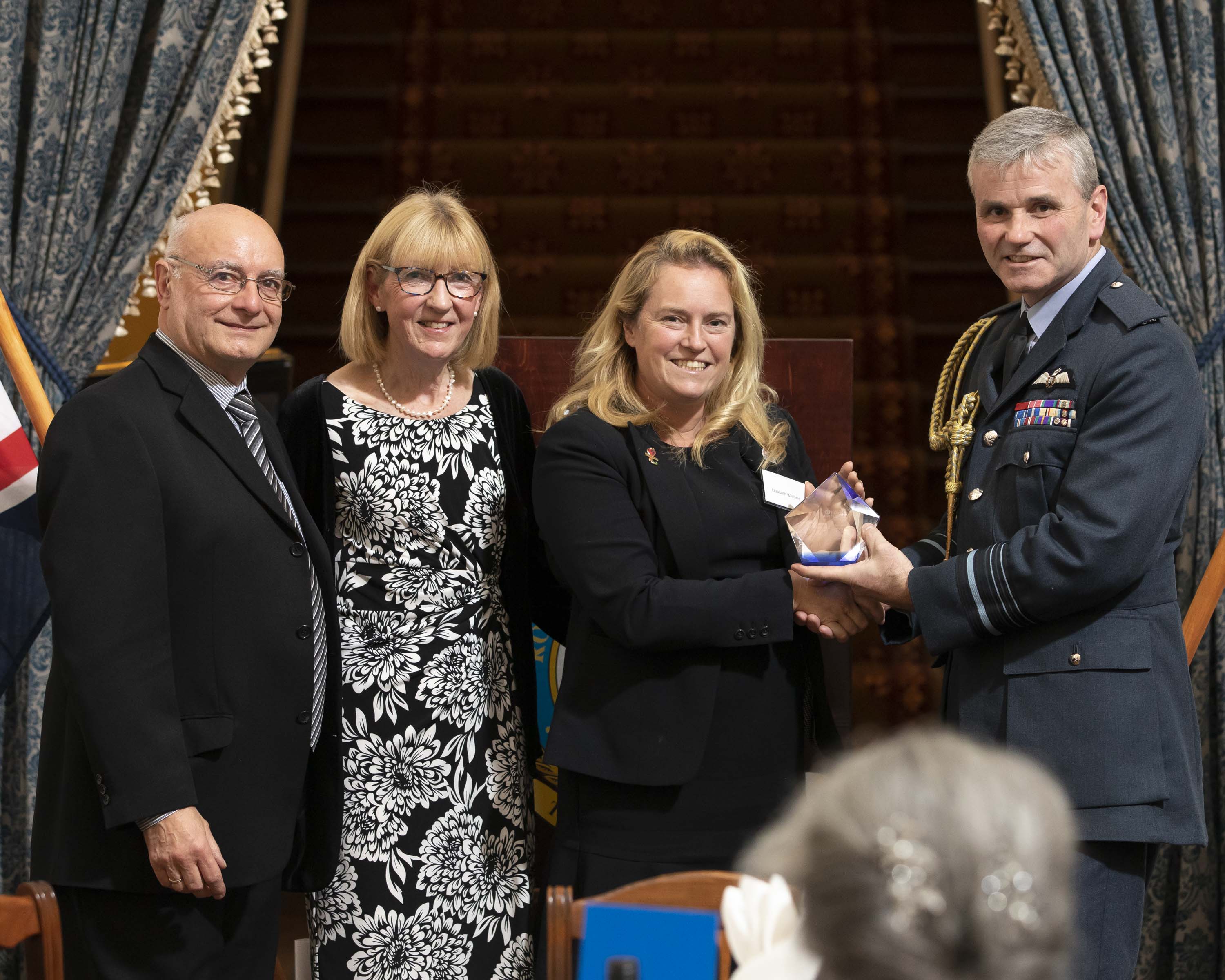 Senior Aircraftwoman Shona Brownlee shakes hands with Air Marshall Andrew Turner while accepting her award, with two others.