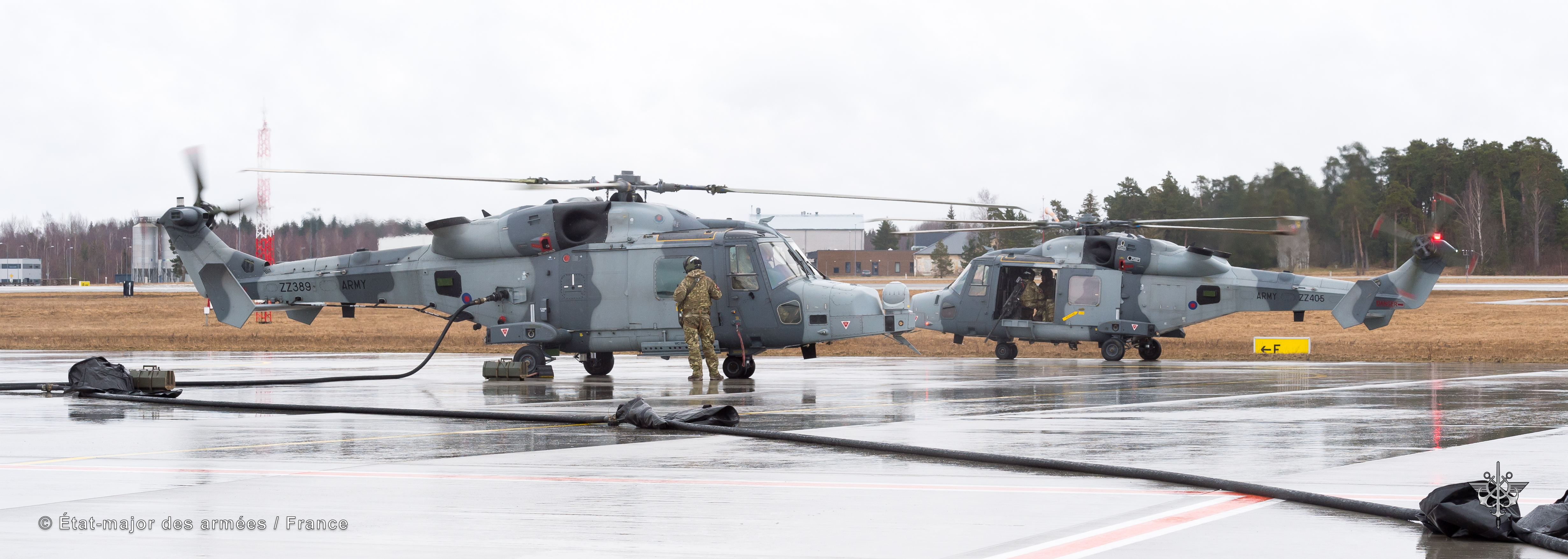 Two helicopters being refuelled on airfield.