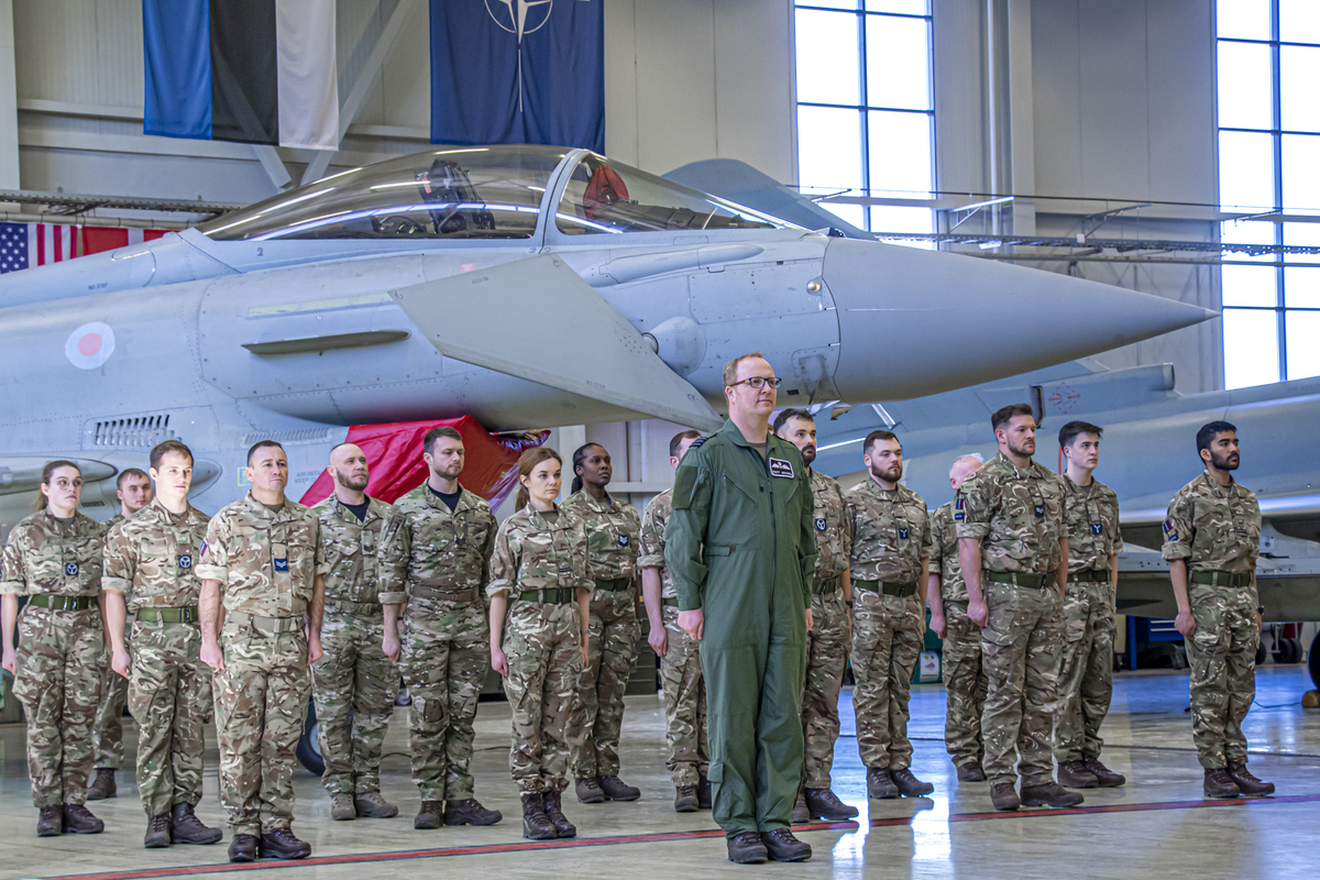 Image shows personnel standing in formation by Typhoons inside a hangar.