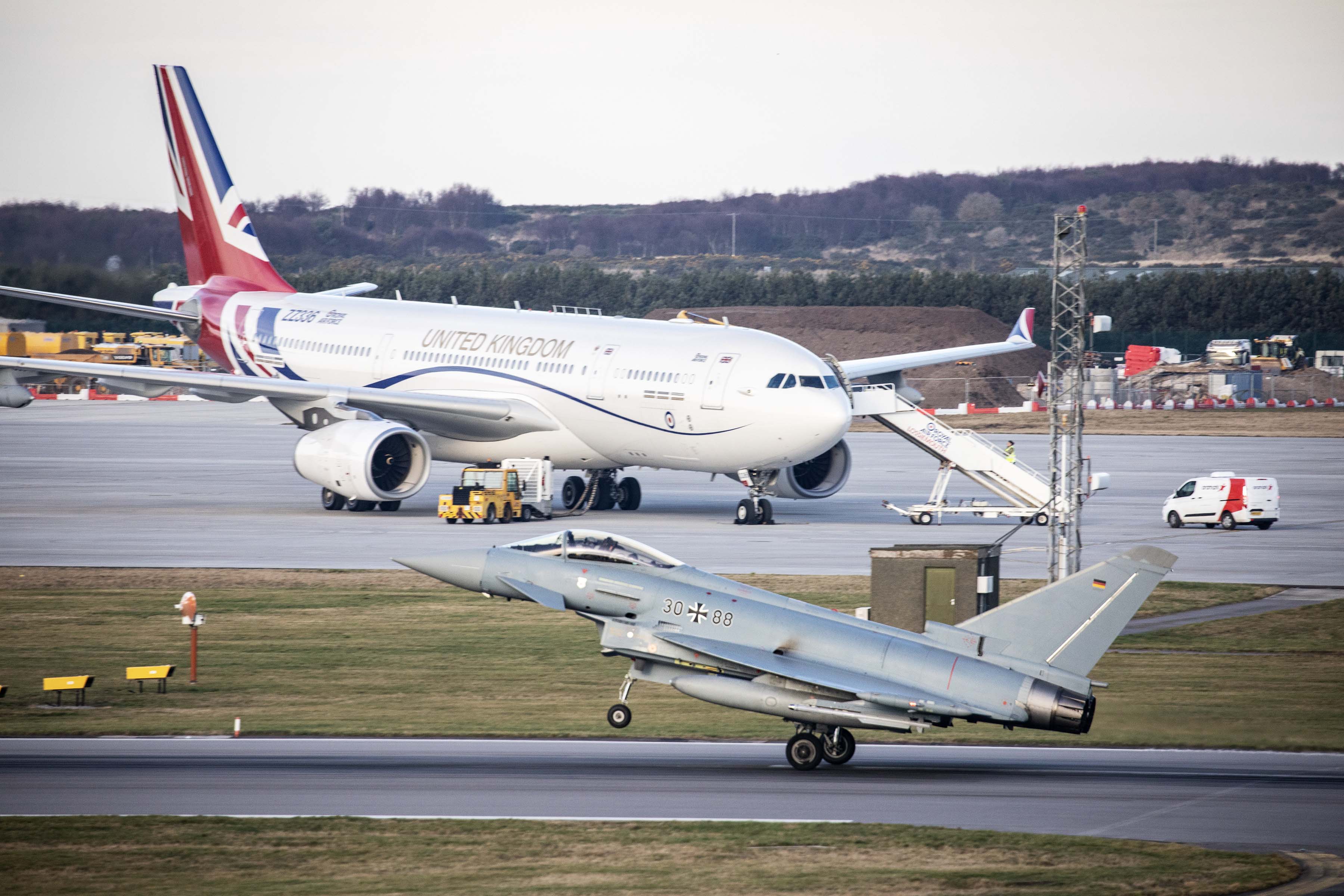 Image shows RAF Voyager on the airfield with a Typhoon taking off over it.