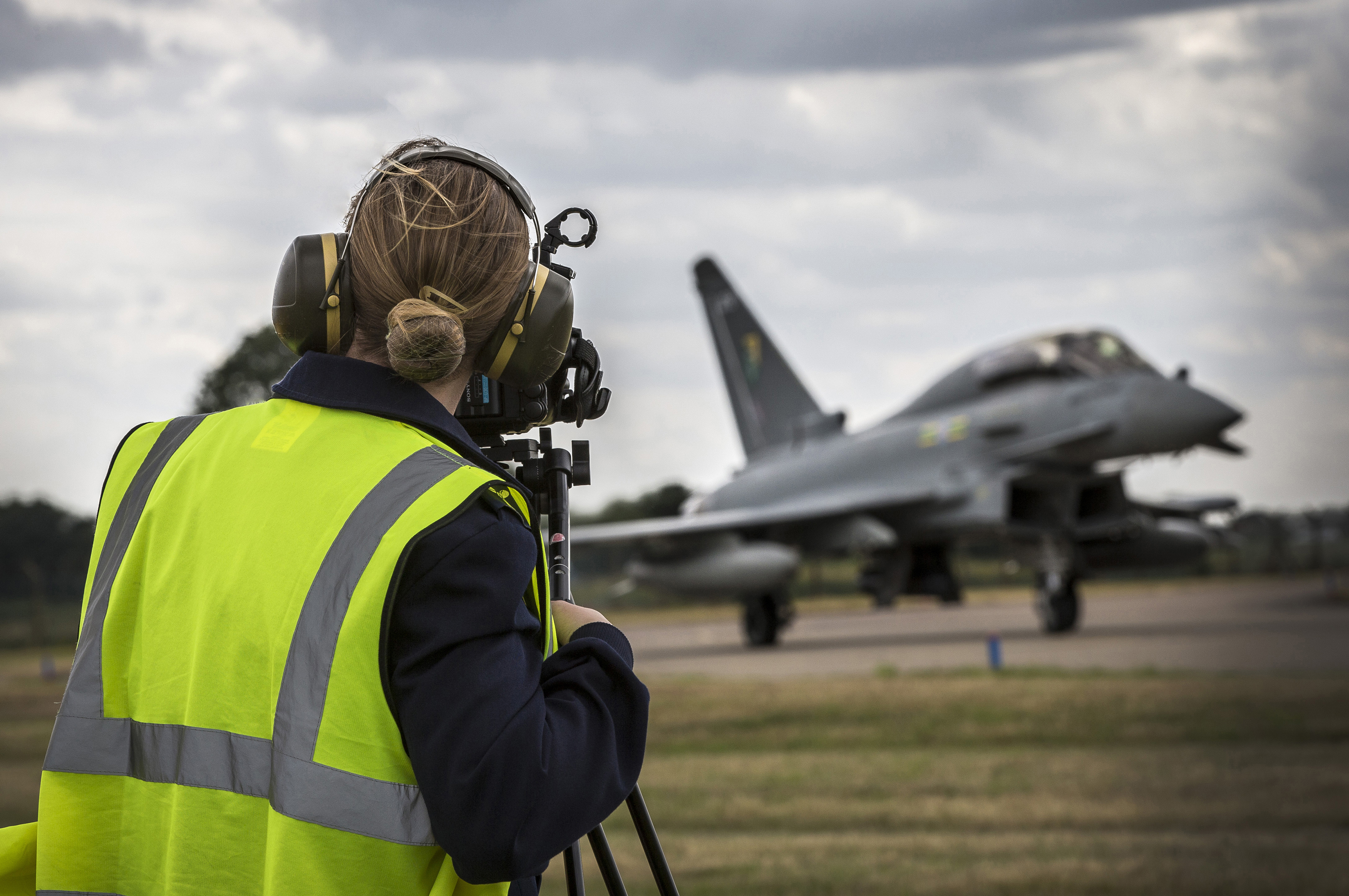 Personnel on airfield with Lightning aircraft in distance.