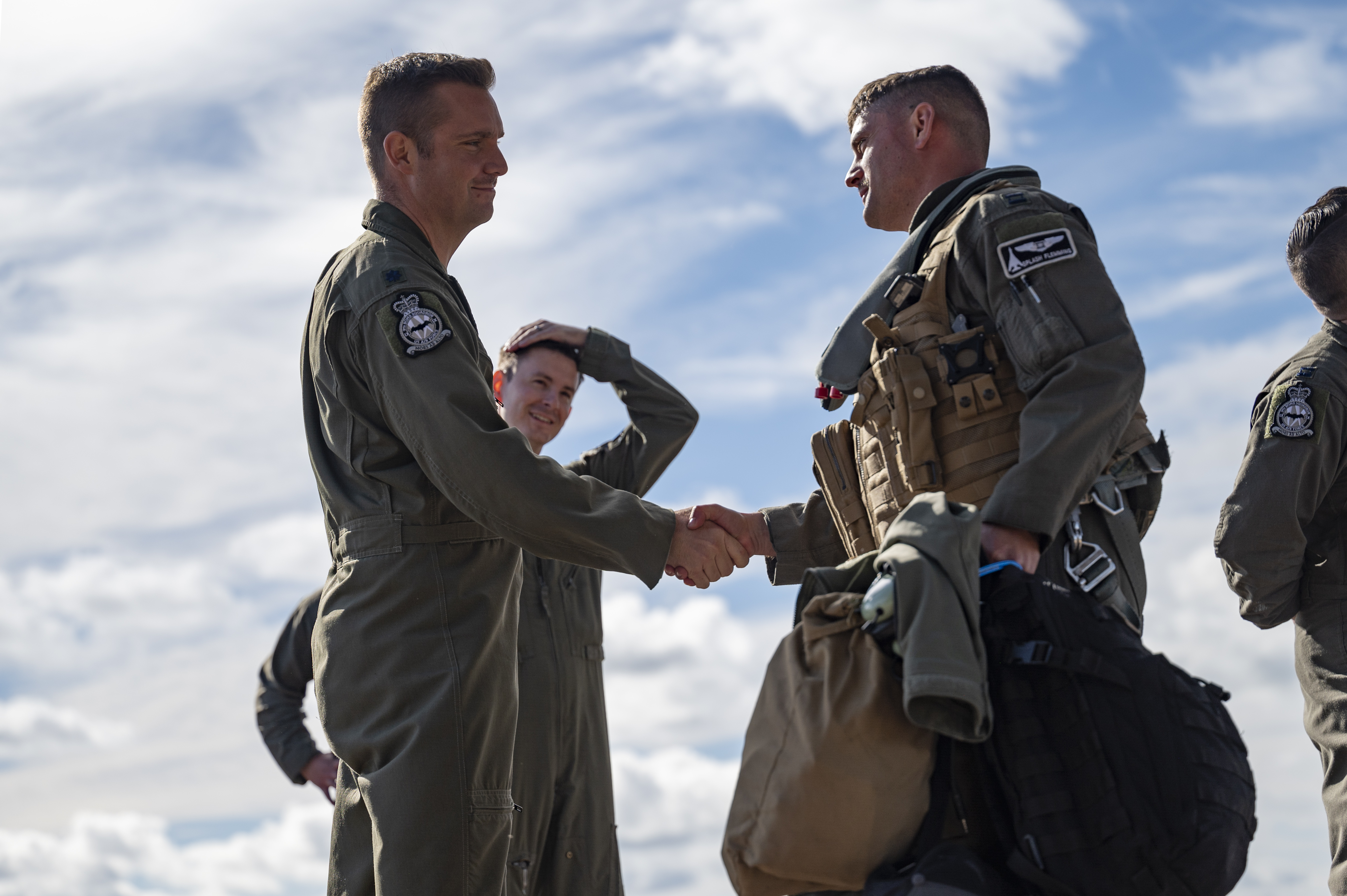 Pilots shake hands as other personnel stand by.