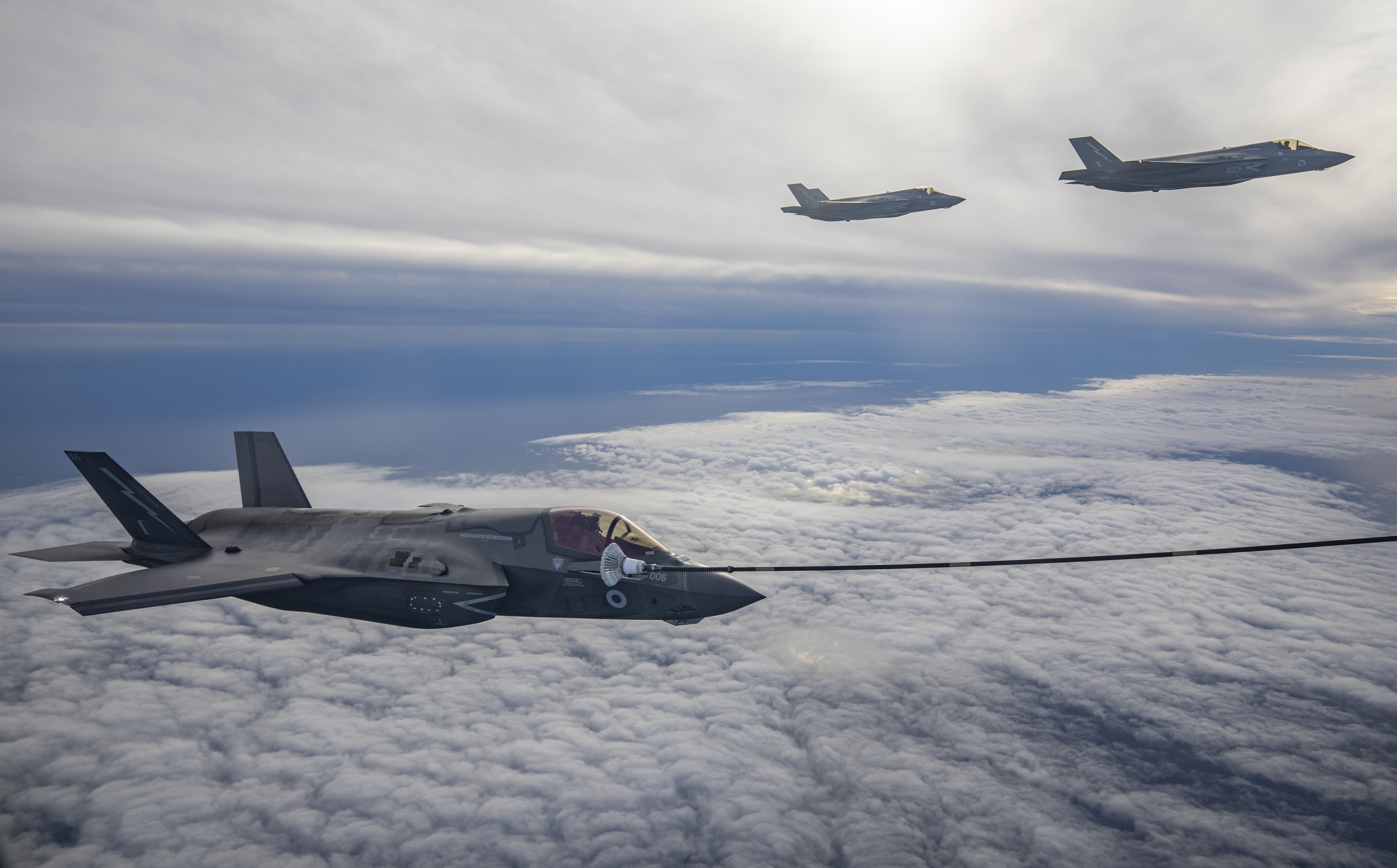 Typhoon during air-to-air refuelling above the clouds. Two Typhoons in the background.