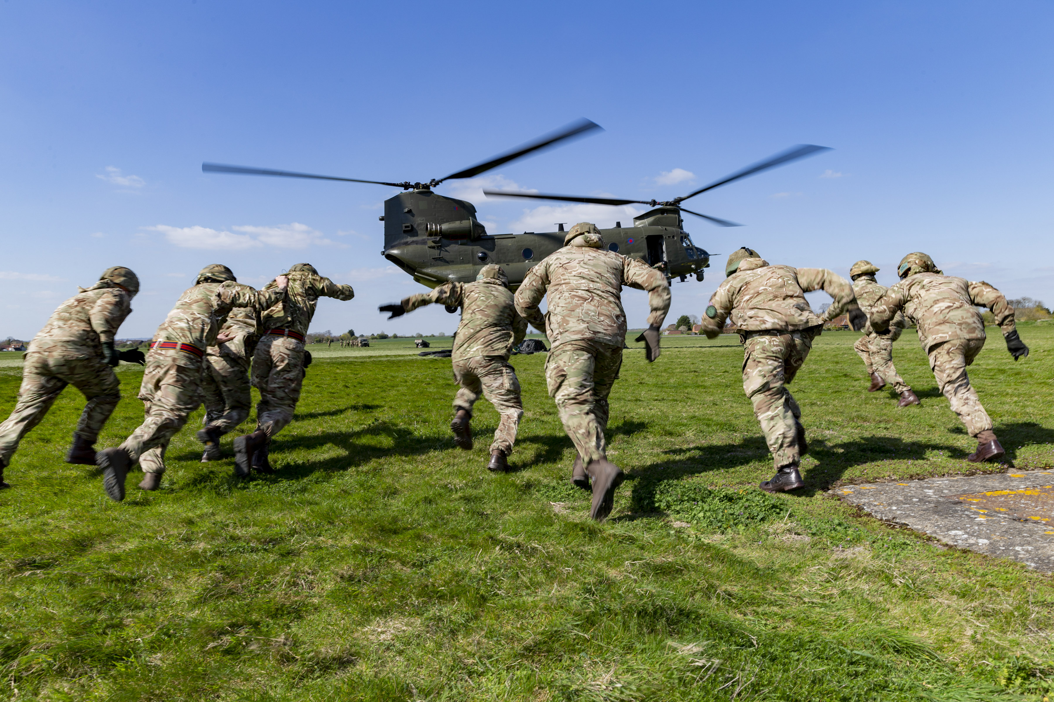 Image shows aviators running towards helicopter ready to take off.