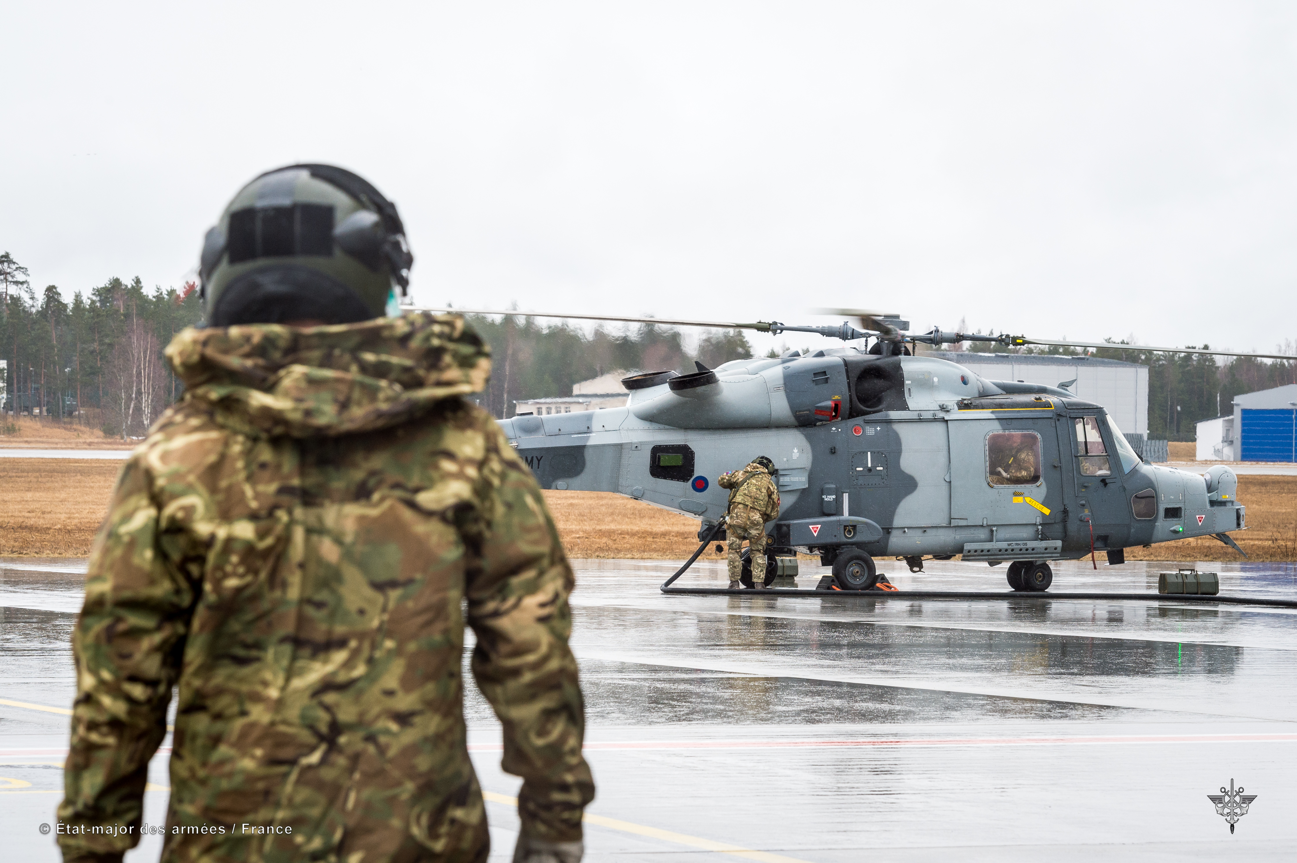 Pilot walks towards helicopter on airfield.