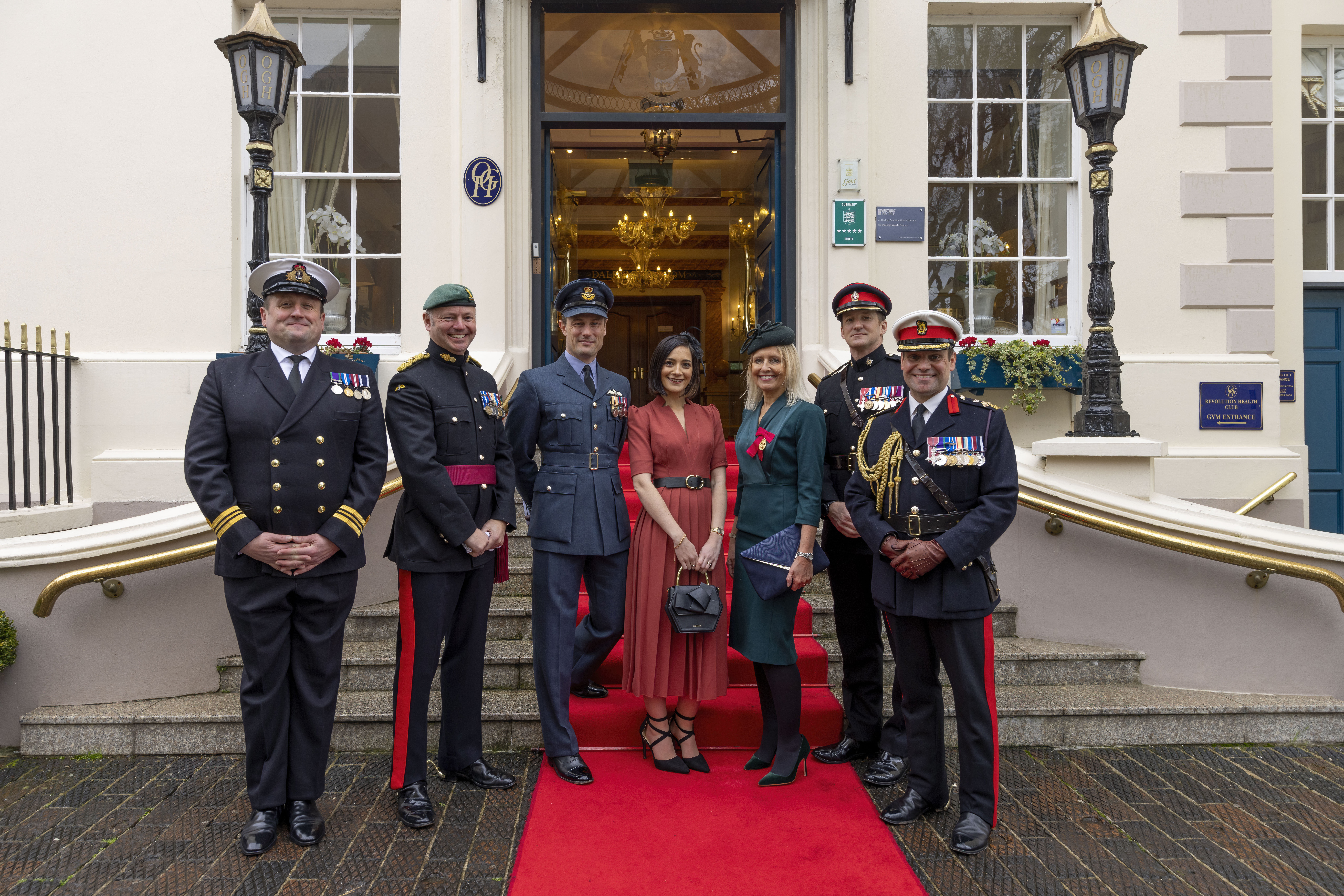 Personnel and Civilians outside building, with red carpet.