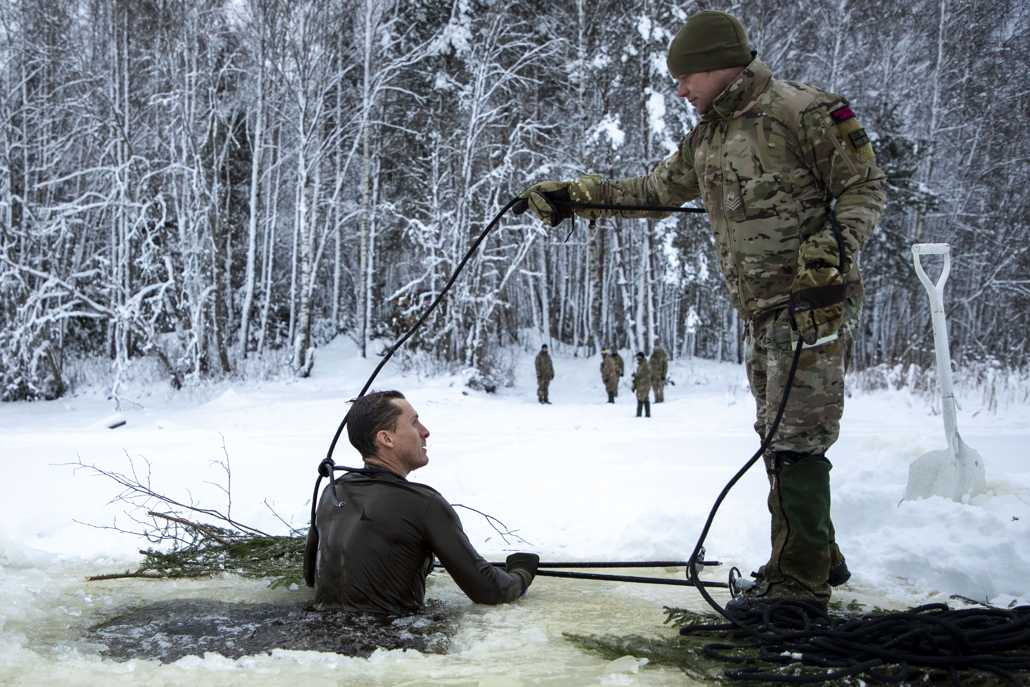 Image shows RAF aviator using rope to pull another out of a frozen lake while on exercise.