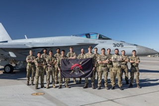 Personnel hold flag in front of aircraft.