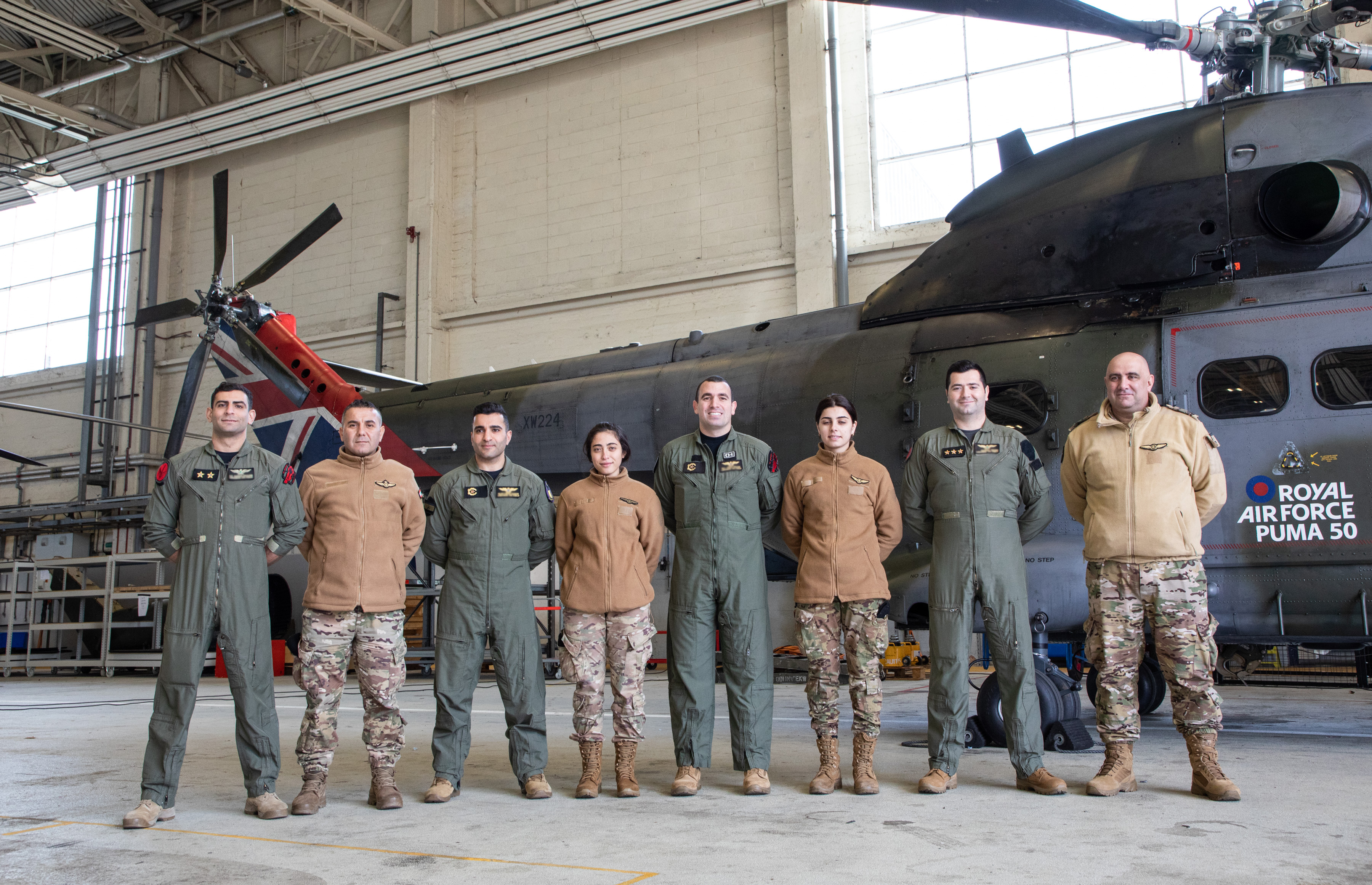 Lebanese Armed Forces personnel line up in front of a Royal Air Force Puma helicopter in a hangar