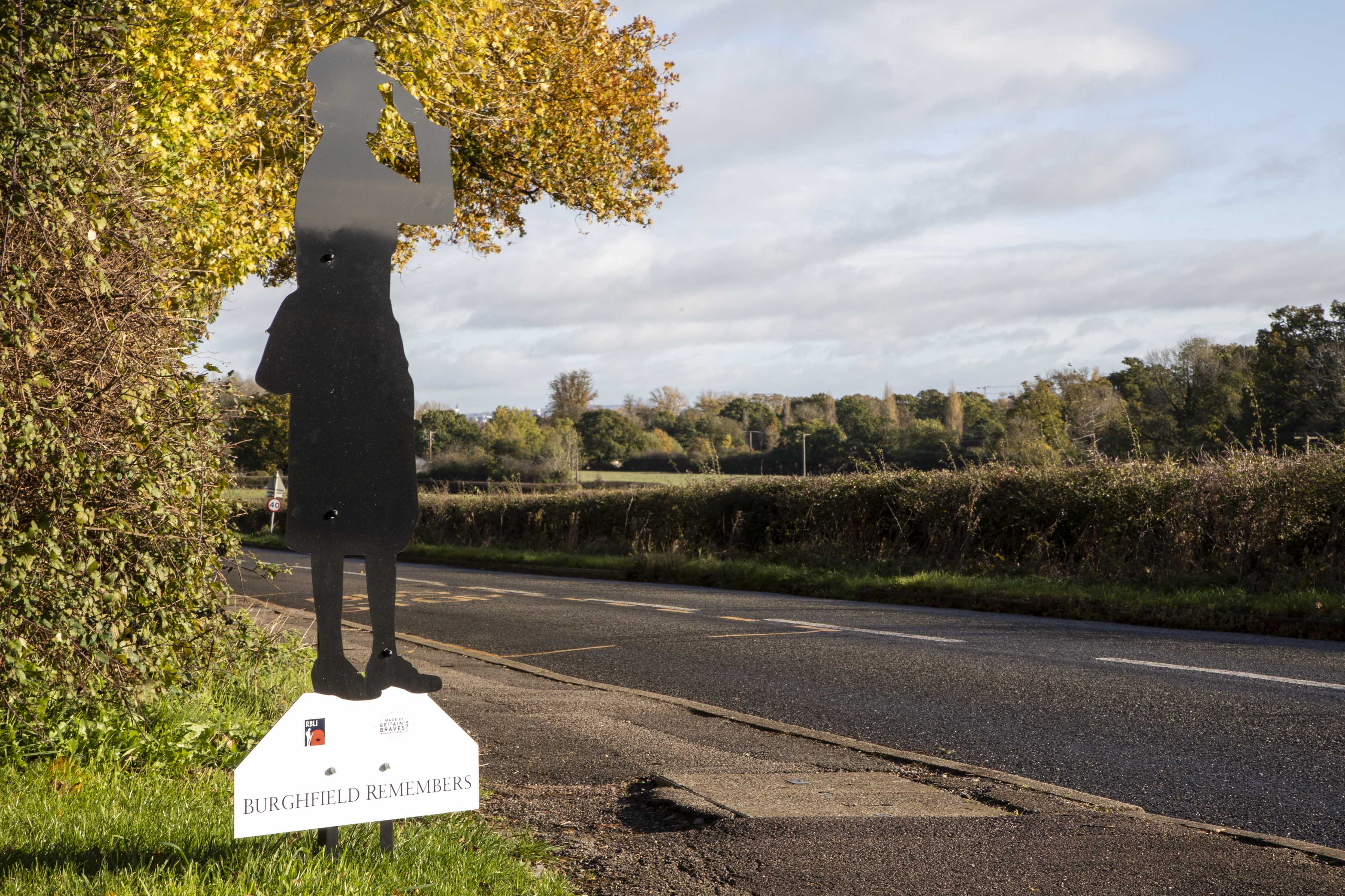 Image shows black silhouette statue by roadside.