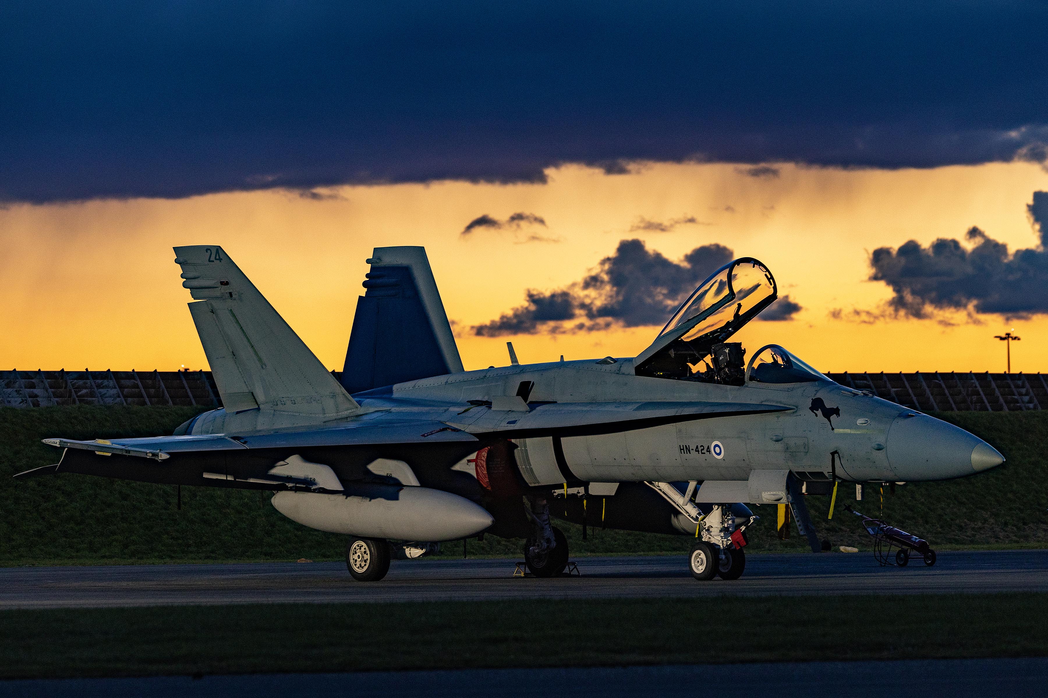Image shows fighter aircraft on the airfield during sunset, with its cockpit open.