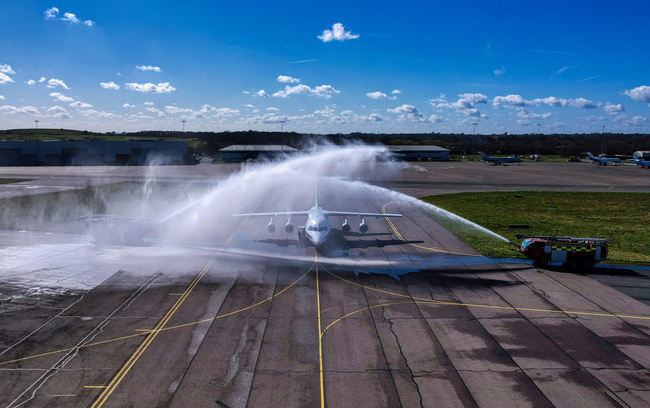 BAe146 aircraft being sprayed with water by fire engines.