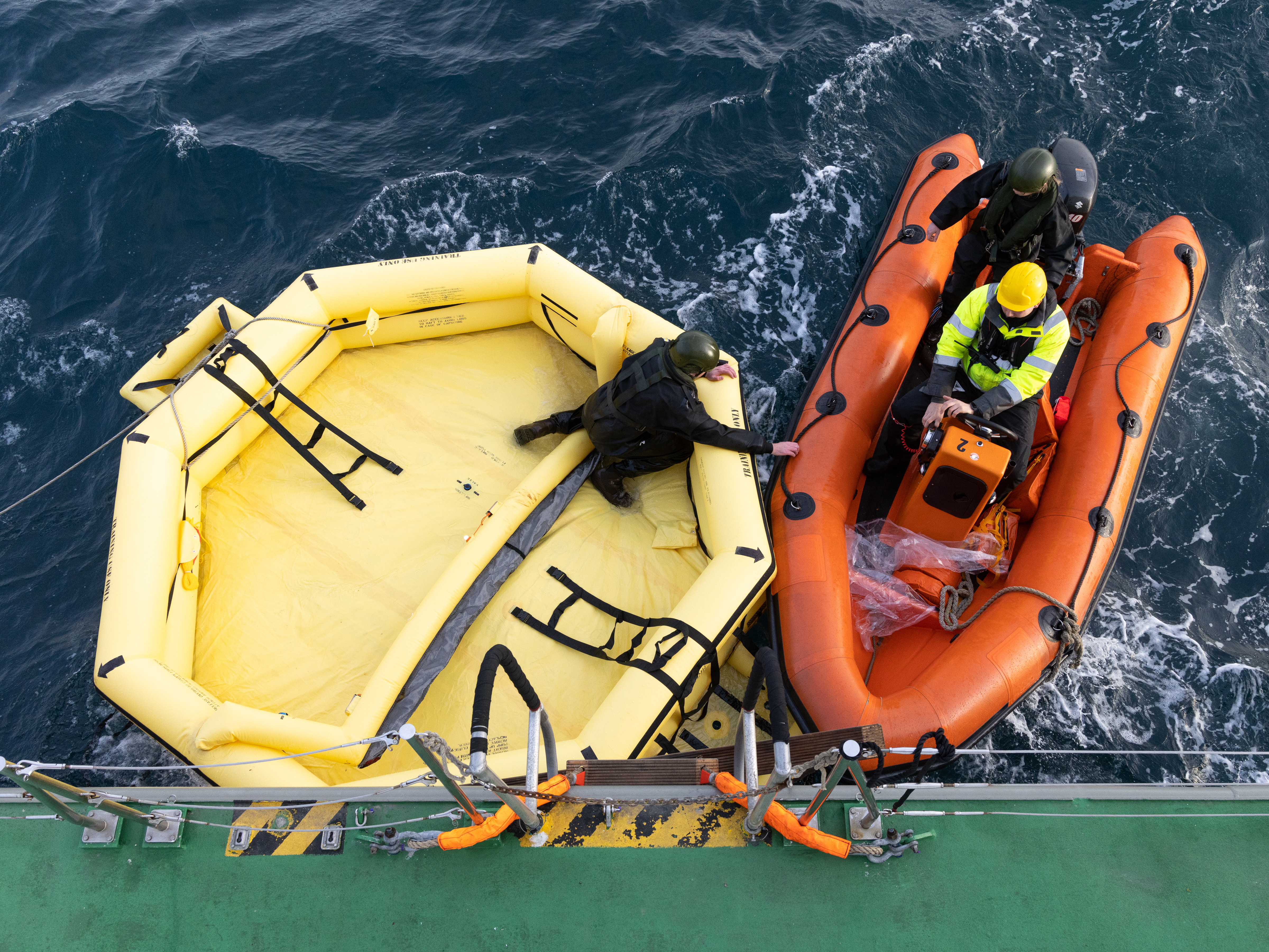Image shows RAF Search and Rescue team and two lifeboats on the sea.
