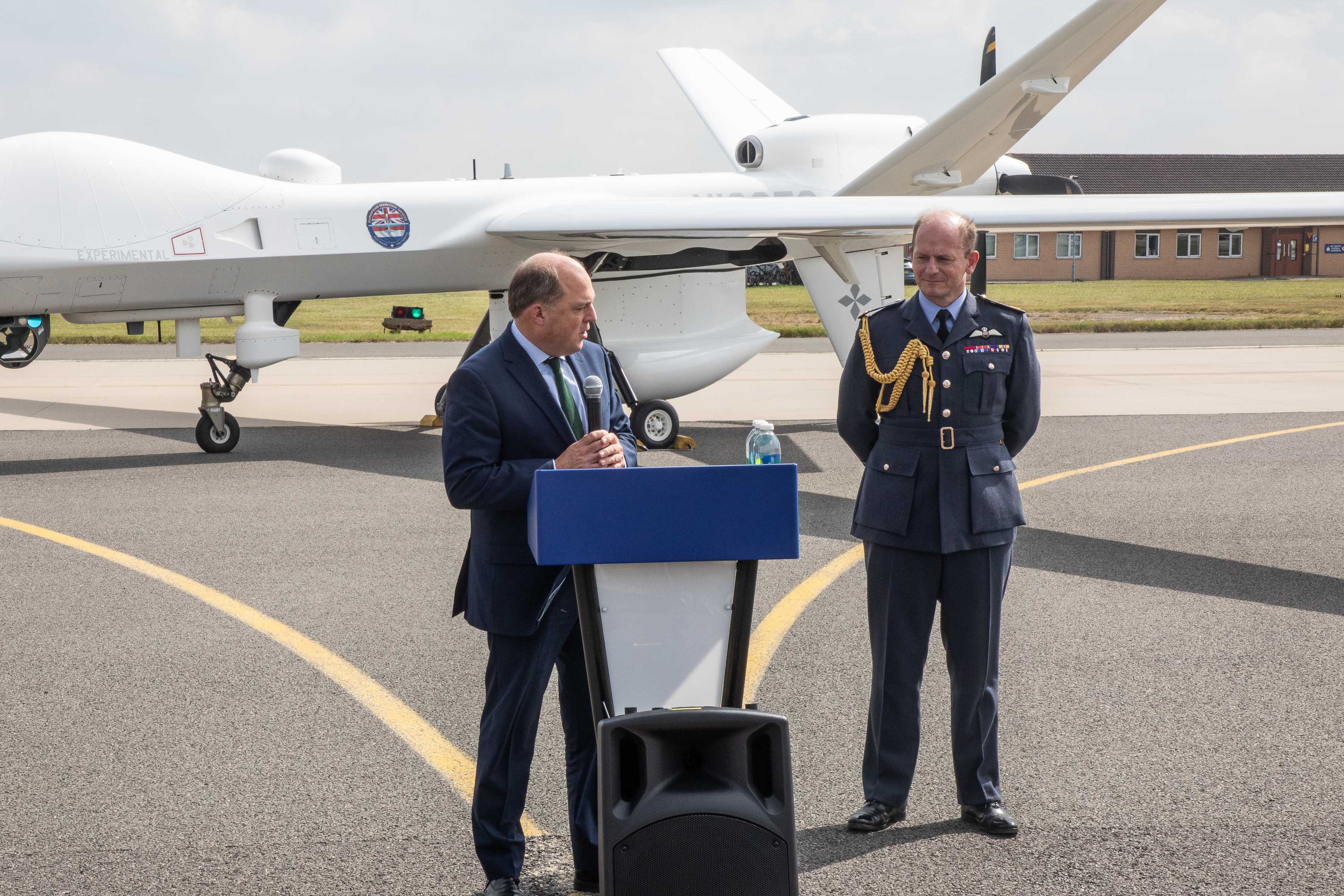 Image shows Defence Secretary Ben Wallace speaking in front of the Protector aircraft.