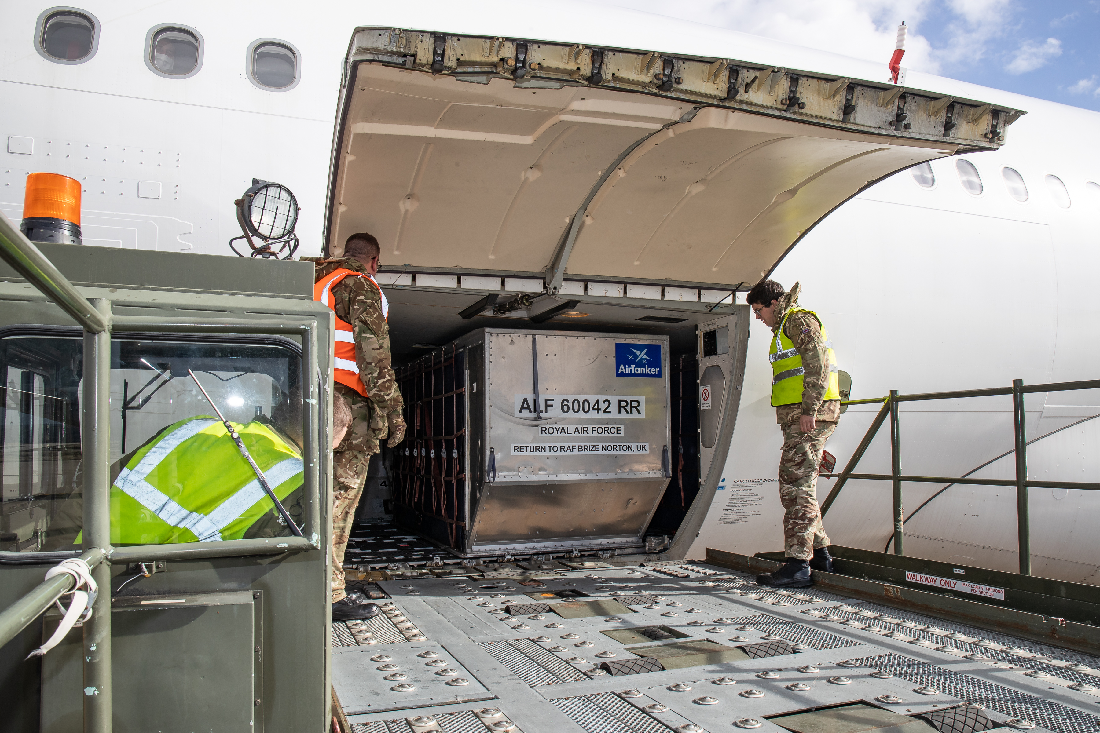 Metal cargo container moved on escalator into carrier aircraft with personnel.