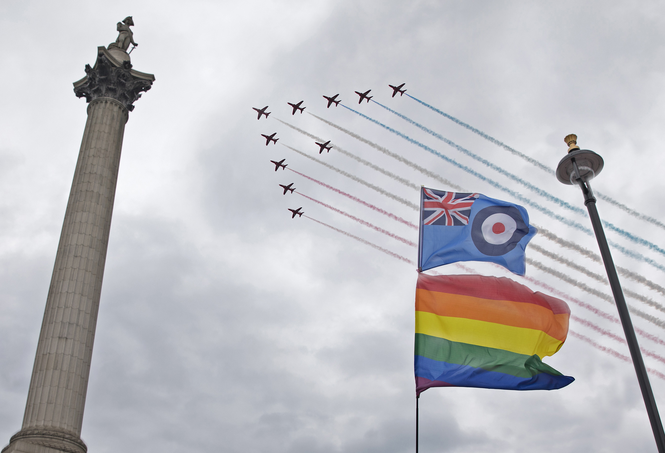 Red Arrows in formation over Nelson's Column and a LGBT rainbow flag.