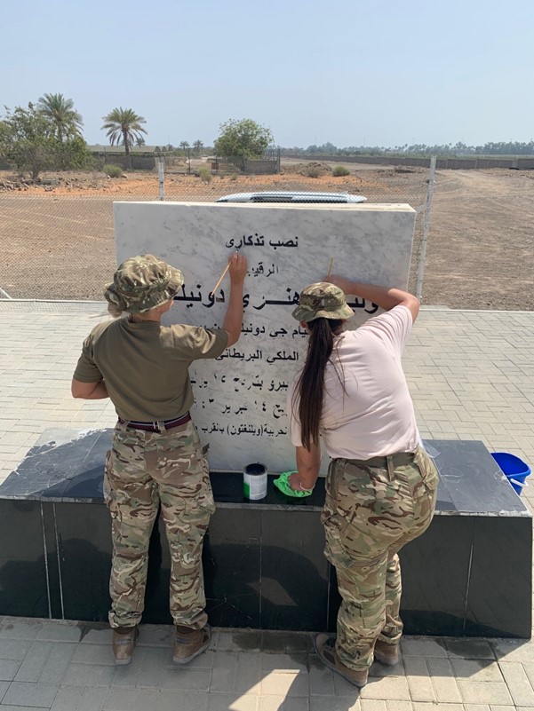 Personnel paint memorial lettering in Arabic.