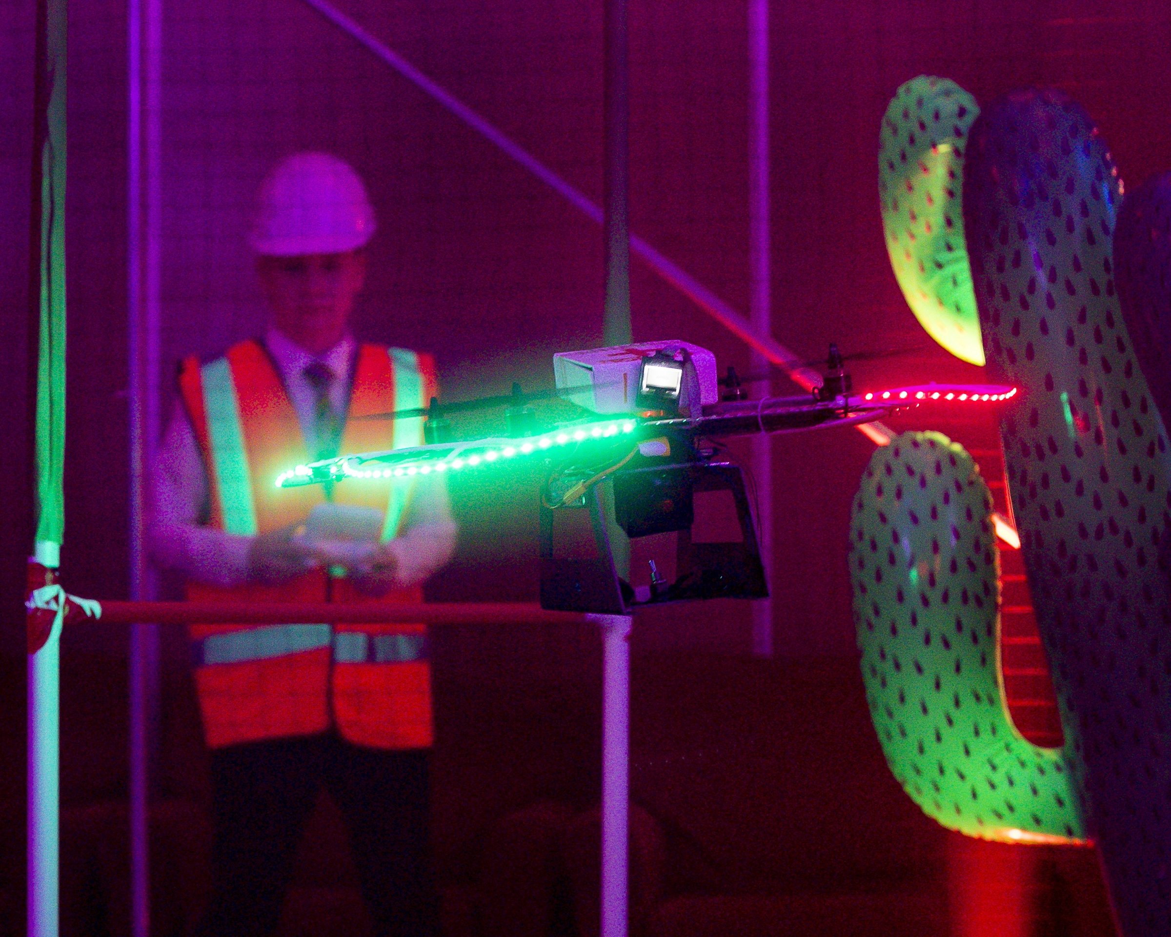 Image shows a school student flying a quadcopter model with LED lights and cactus tree obstacles.