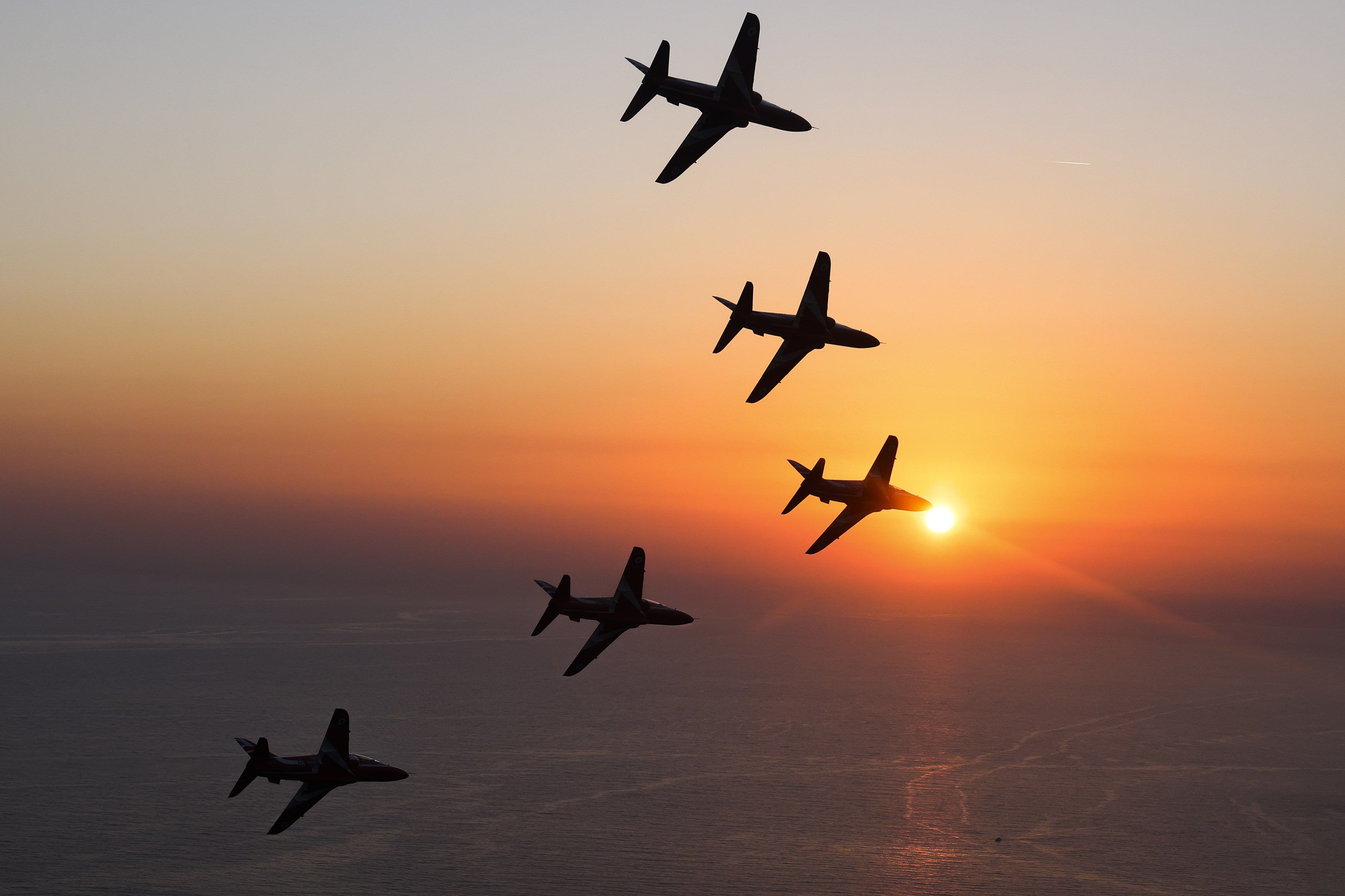 RAF aircraft flying in formation towards the sunset