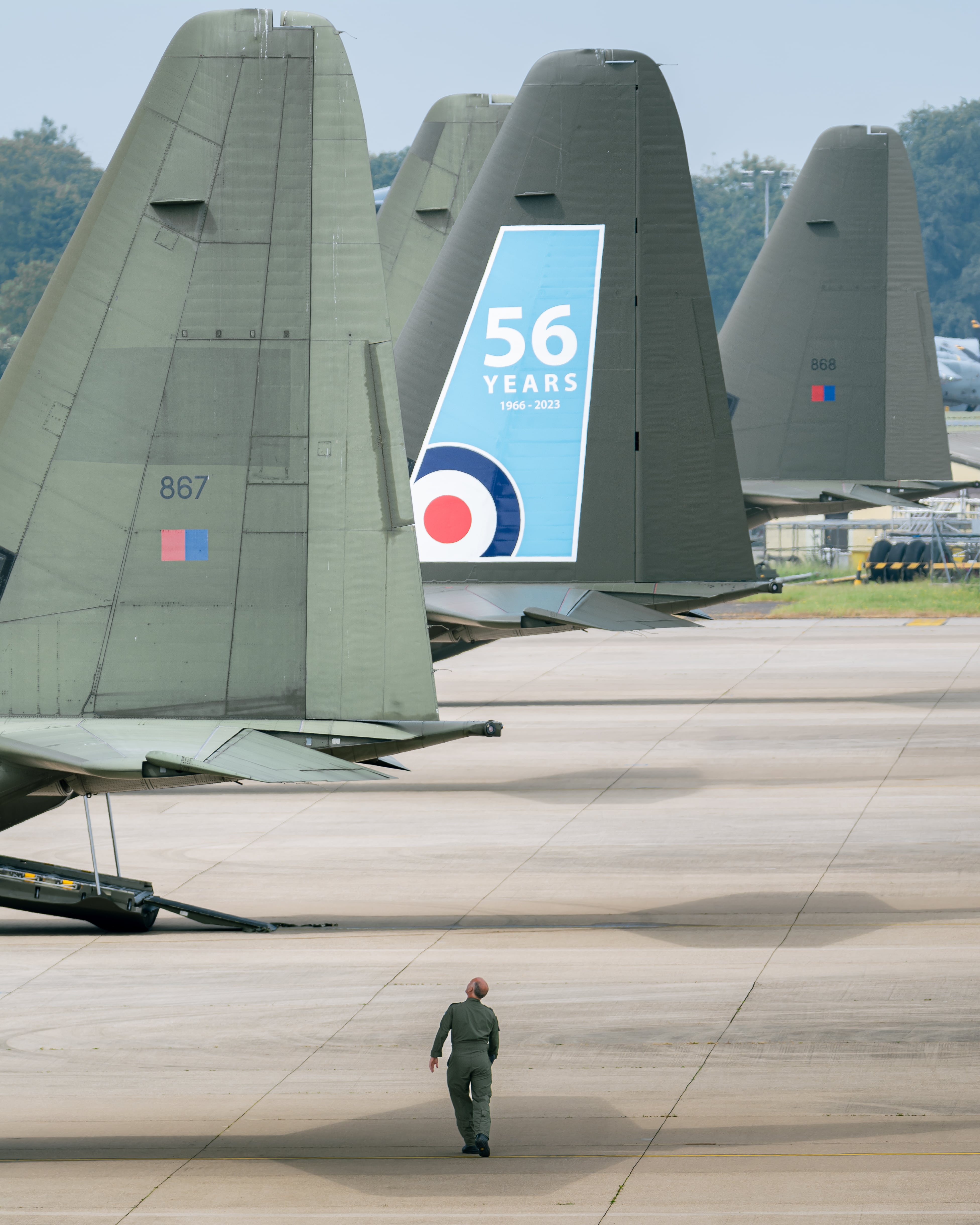Man walking beneath the tails of aircraft, looking tiny in their shadow