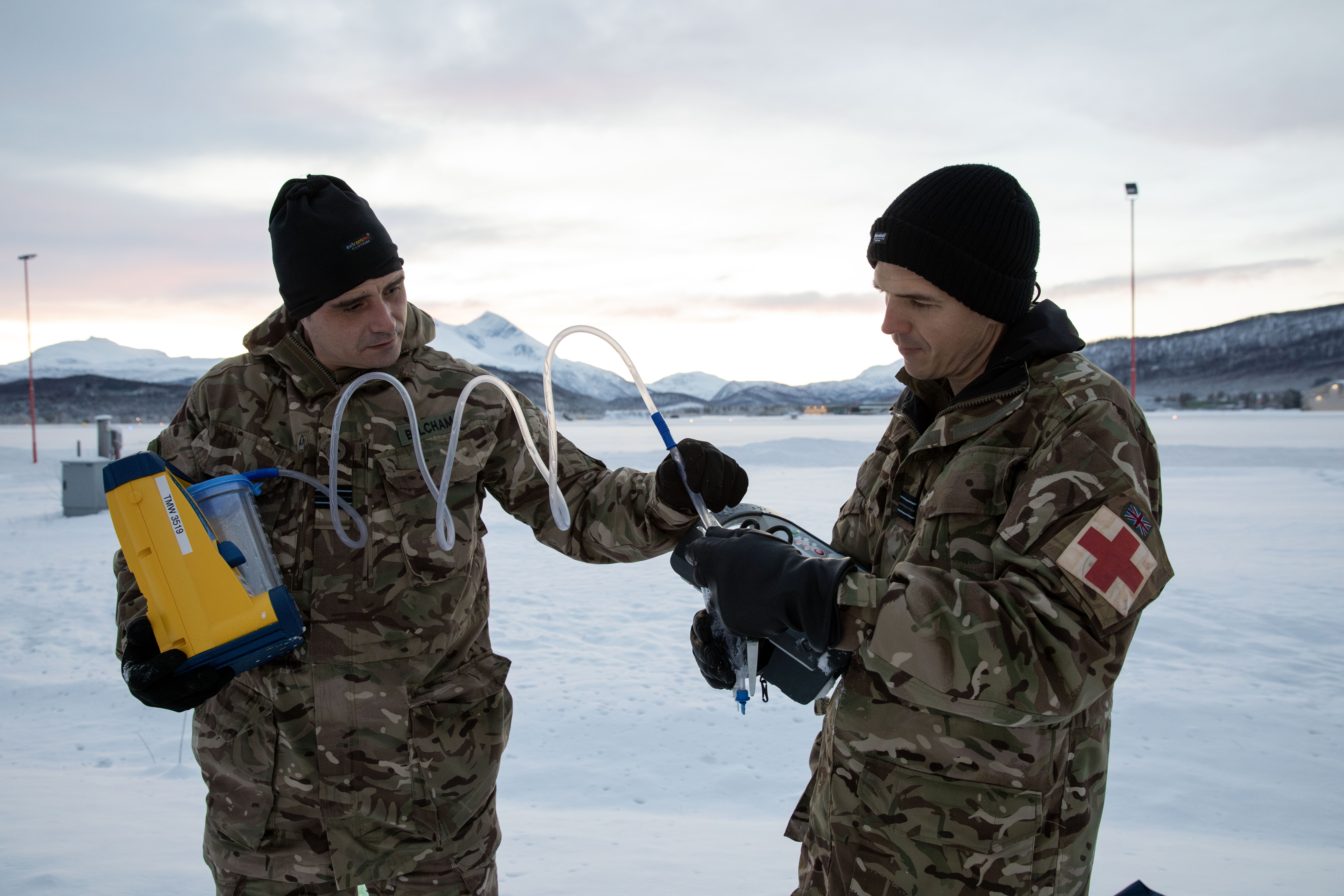 2 RAF medics working with a piece of medical equipment in the snow