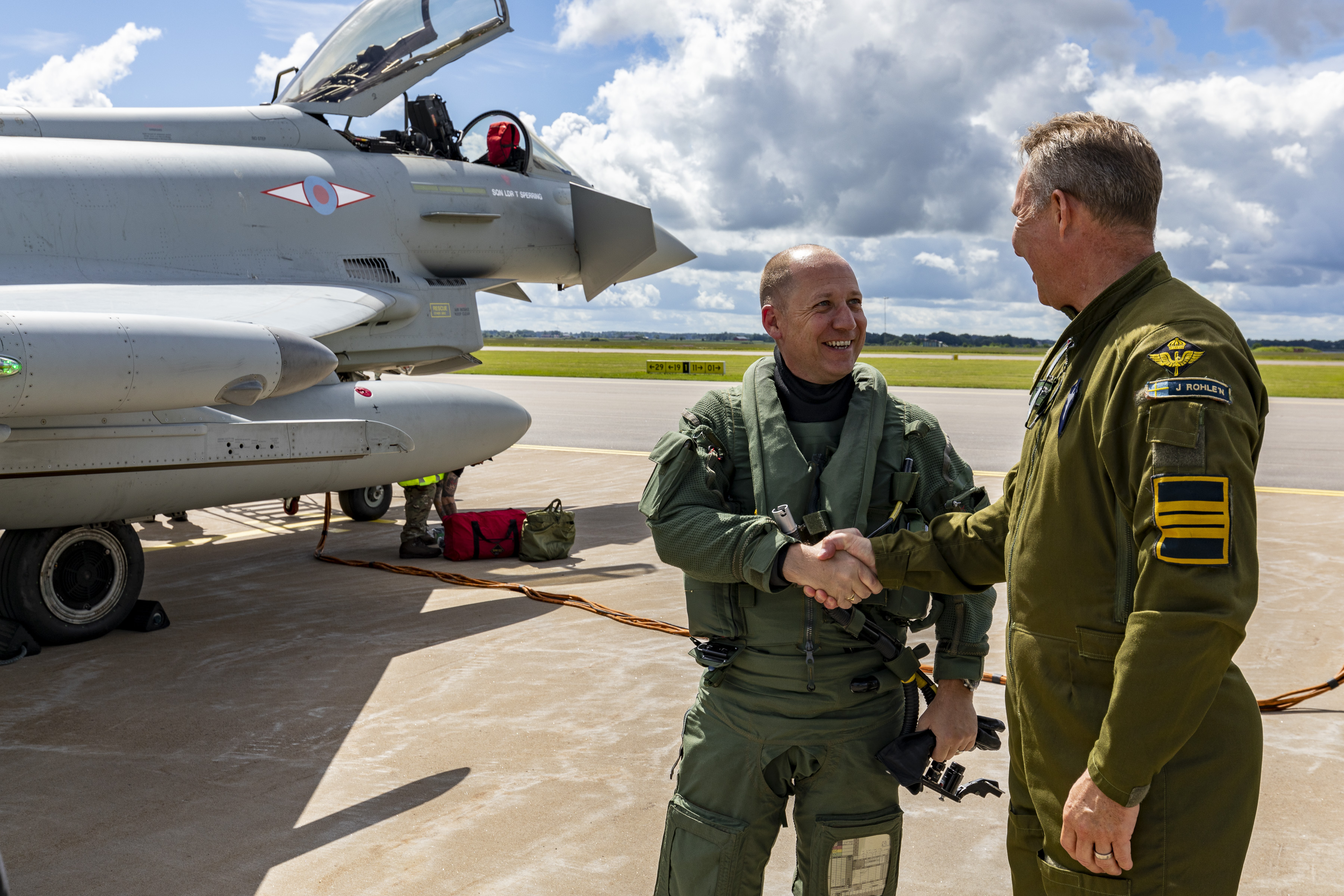 RAF and SwAF pilots shaking hands in front of a Typhoon aircraft