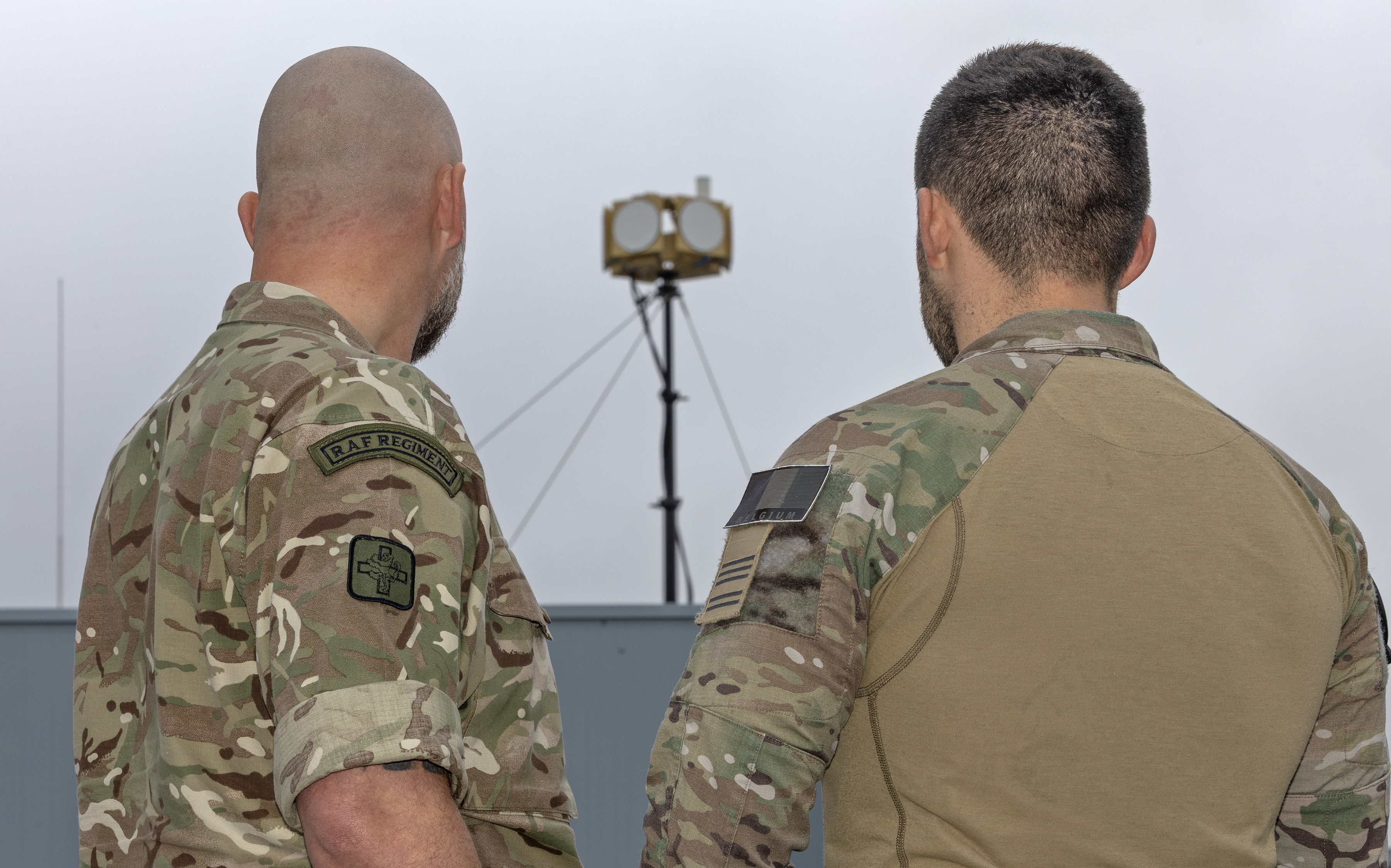 Back view of two service personnel, one British and one Belgian.