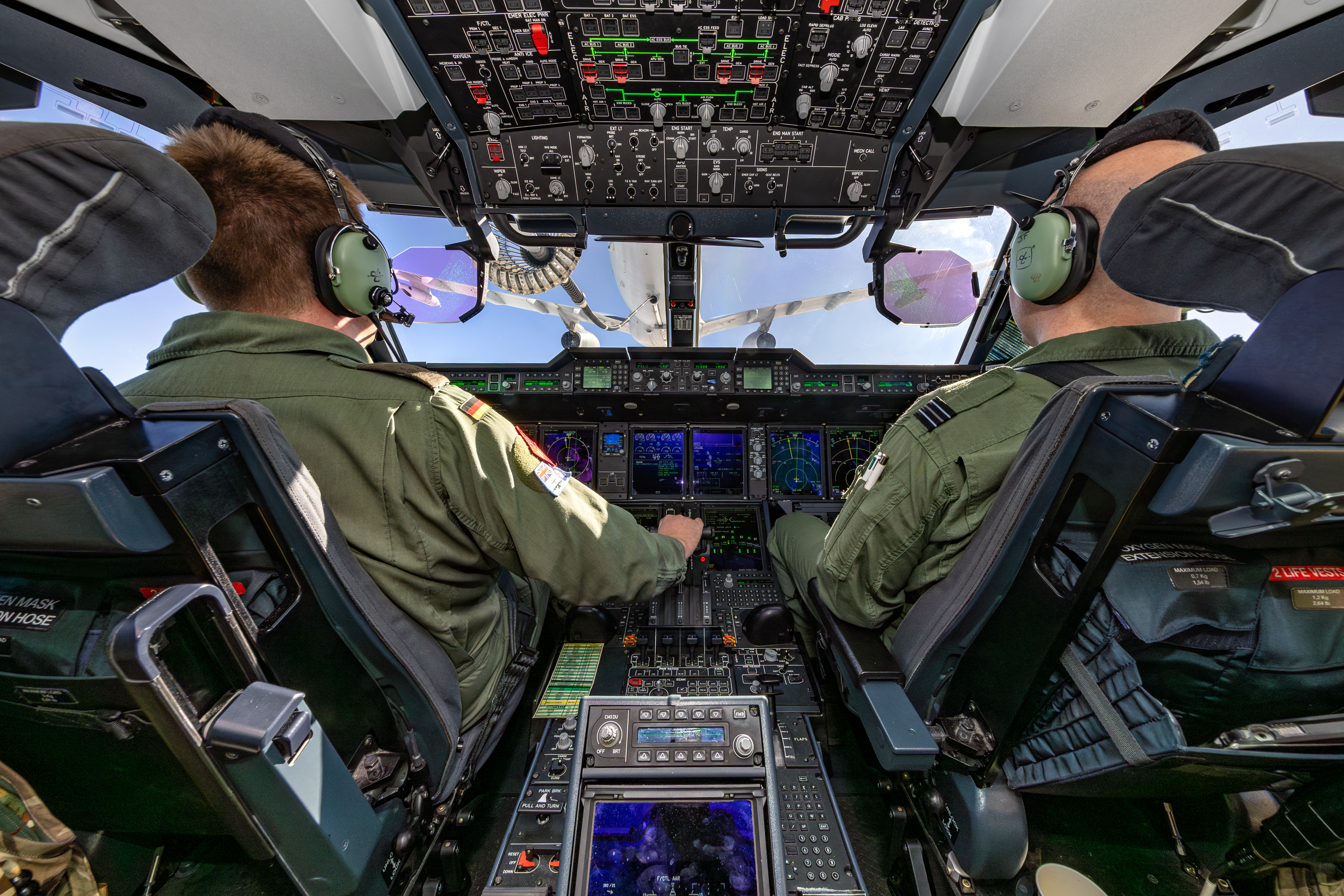 "Pit Stop". A view from the cockpit of a RAF aircraft engaged in air-to-air refuelling. Two aviators, one from the RAF and one German are sat in the cockpit.