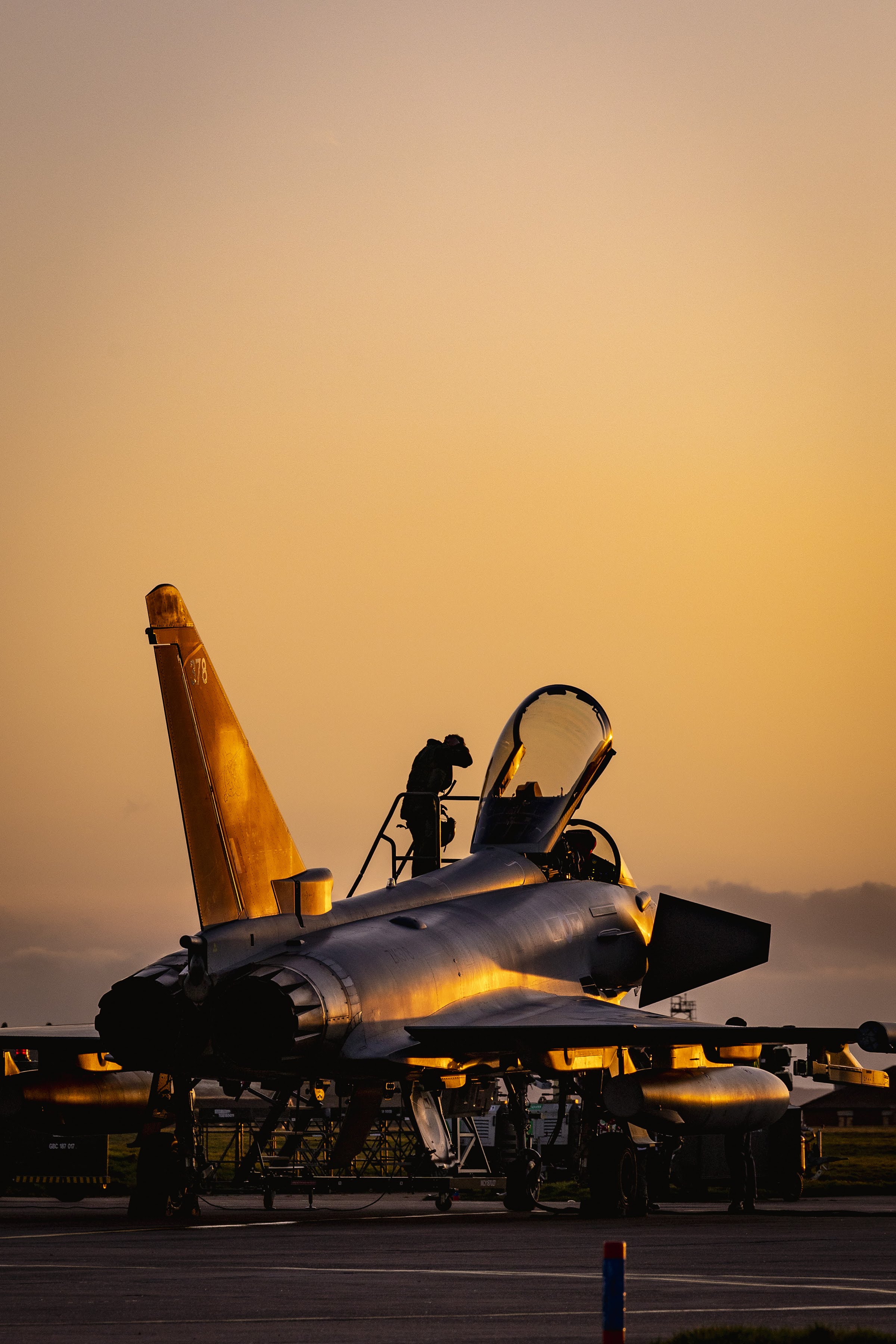A member of a Typhoon crew standing on top of the aircraft making final checks.