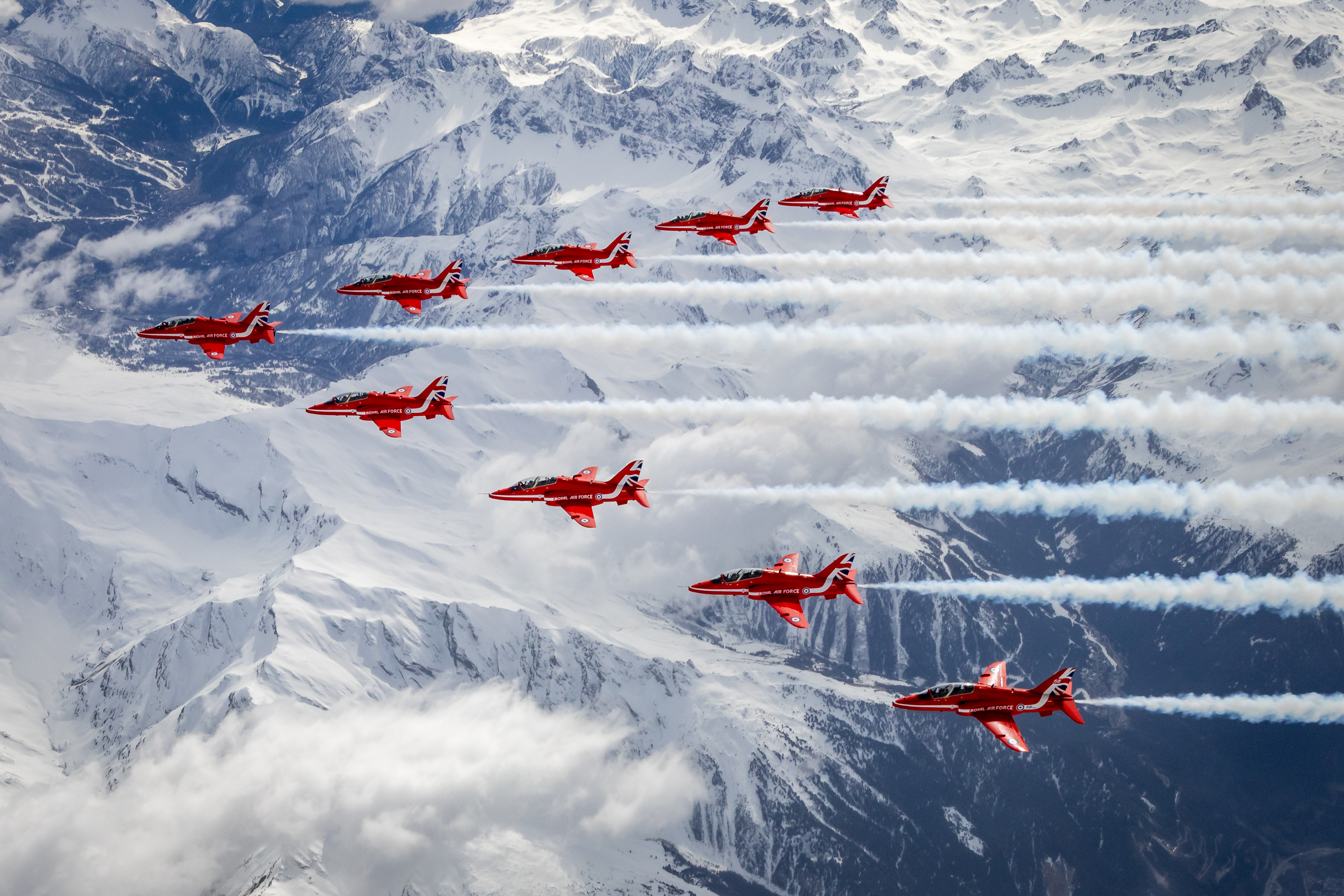 "Cool As Ice". Nine Hawk T1s of the Red Arrows fly in formation over a snowy mountain range.