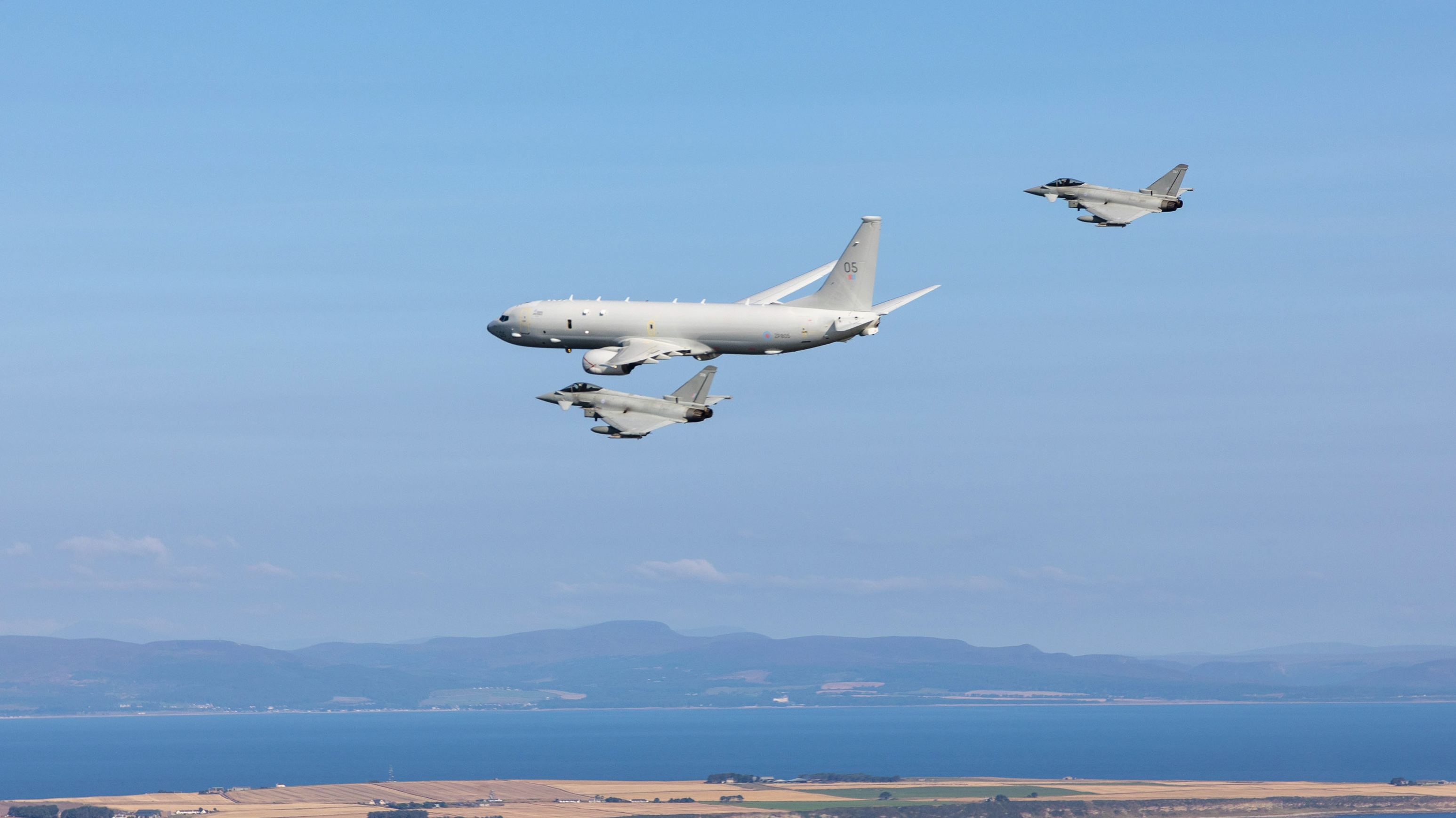 RAF Poseidon mid-flight being flanked by RAF Typhoons.