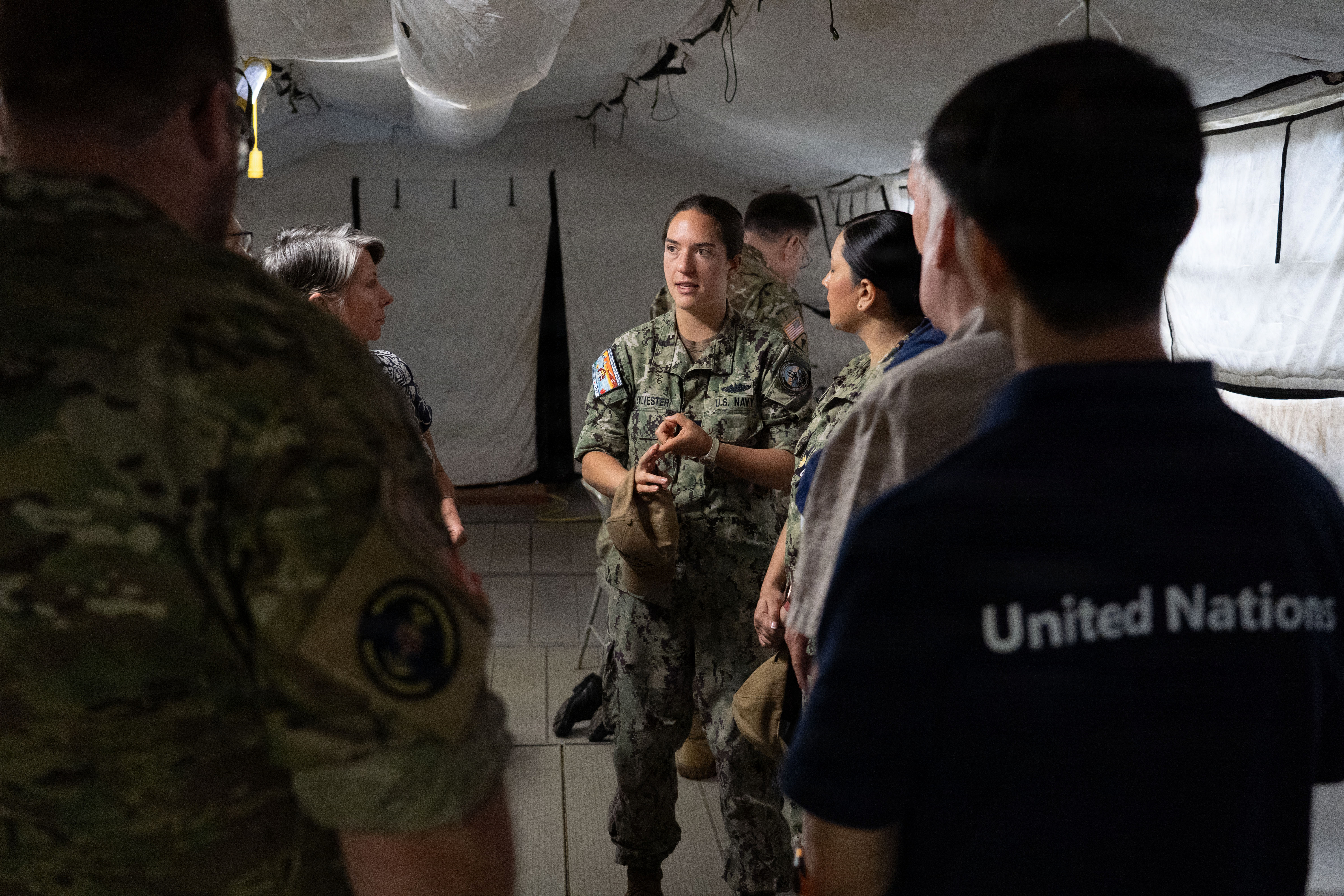 A US Navy service person talks to a multi-national team on RIMPAC.