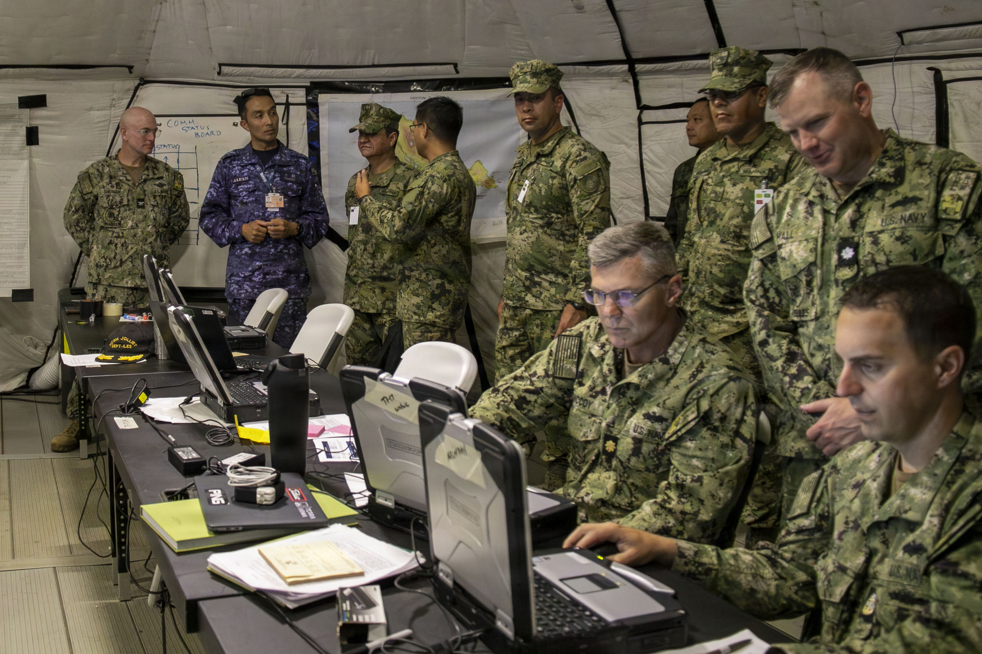A multi-national team of officers work together in a tent on Rim of the Pacific exercise.